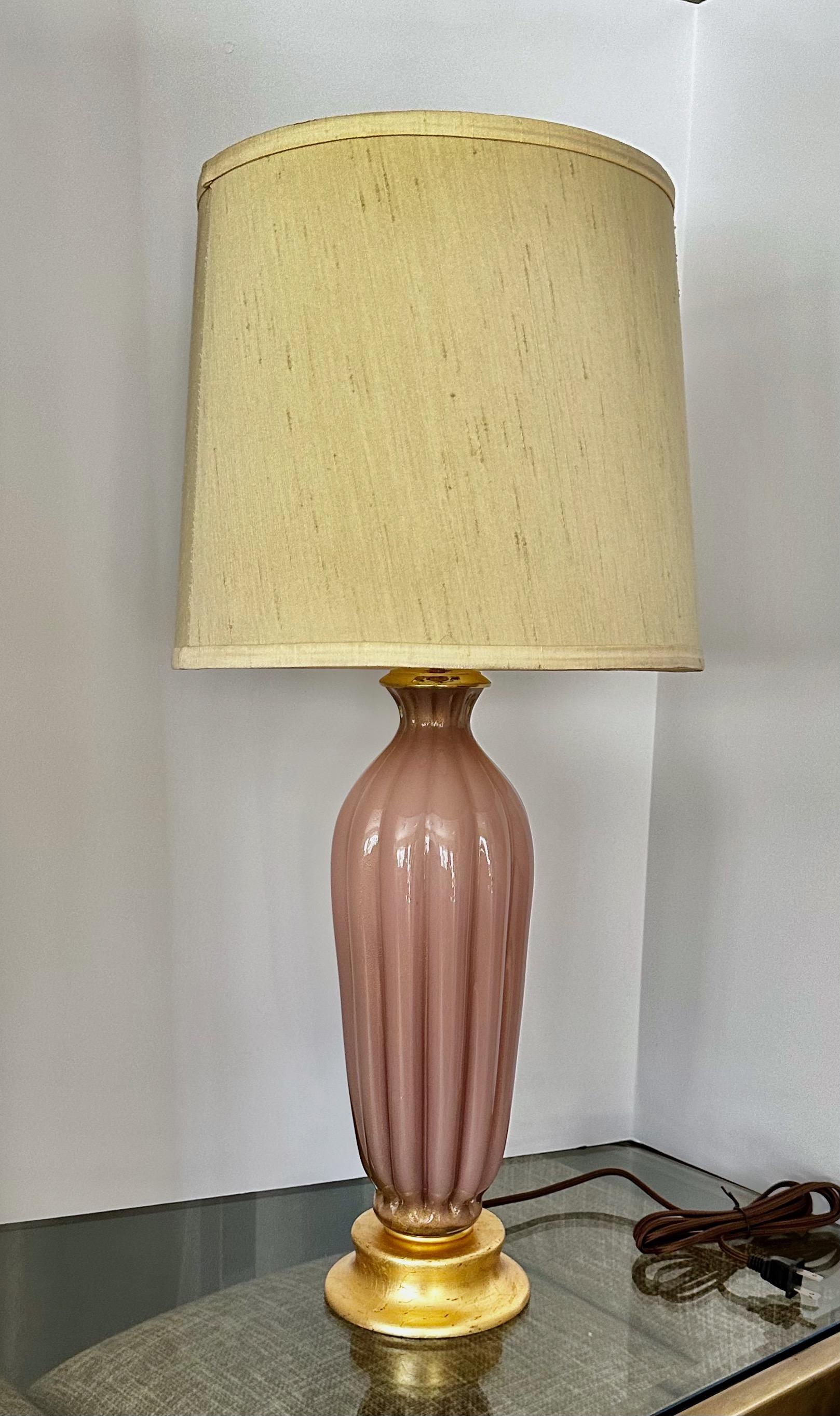 Murano ribbed pinkish/mauve colored glass table lamp with gold inclusions. Glass body rest on custom giltwood base. Newly wired for US with new brass fittings including 3 way socket and rayon covered cord.

Measures: 21