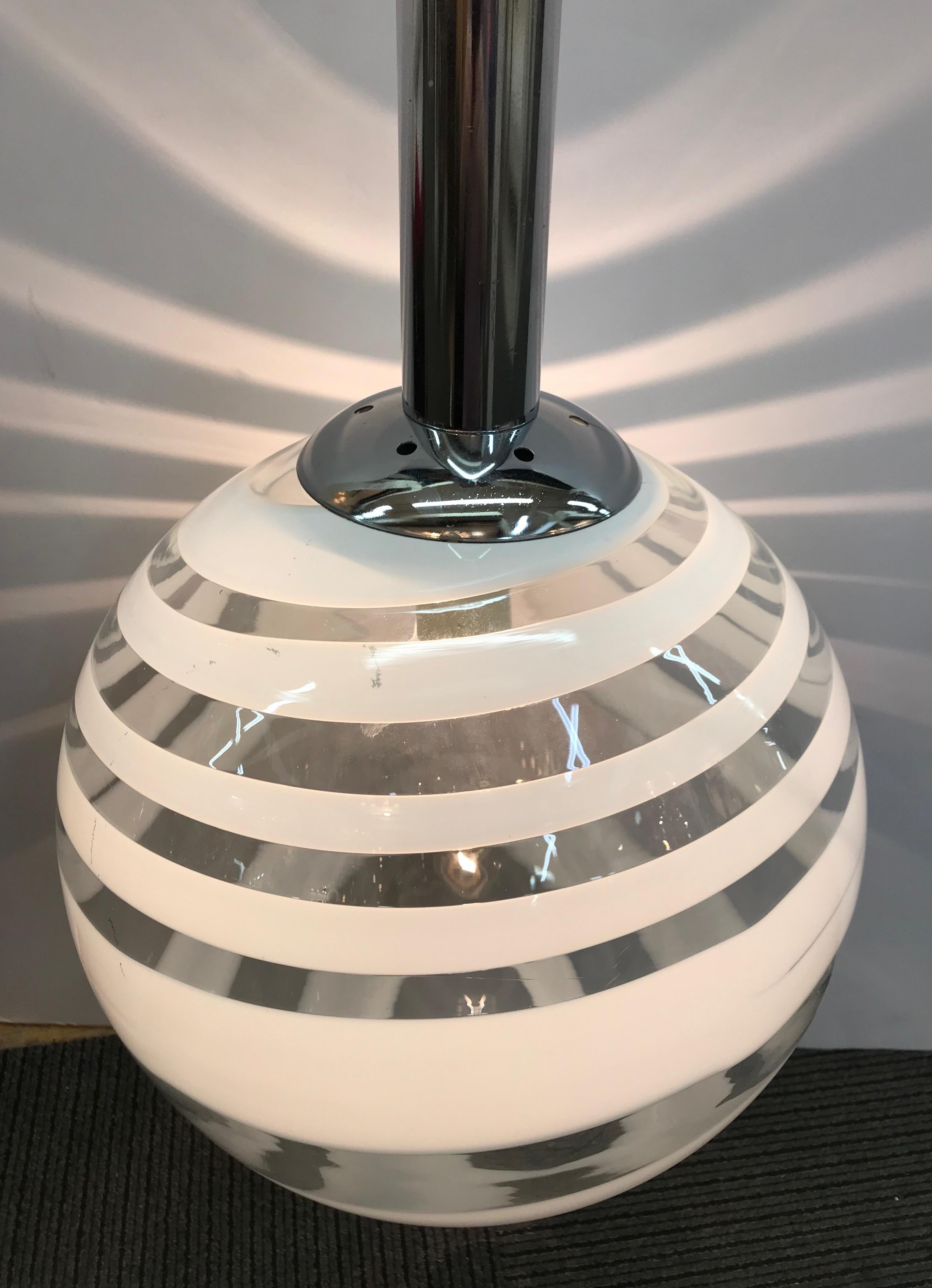 A beautiful Murano, Italy handblown clear with white spiral glass globe shade pendant light, circa 1970. Original chrome tube top mount that supports the glass globe shade. The pendant is suspended on steel cord with white electrical corn next to