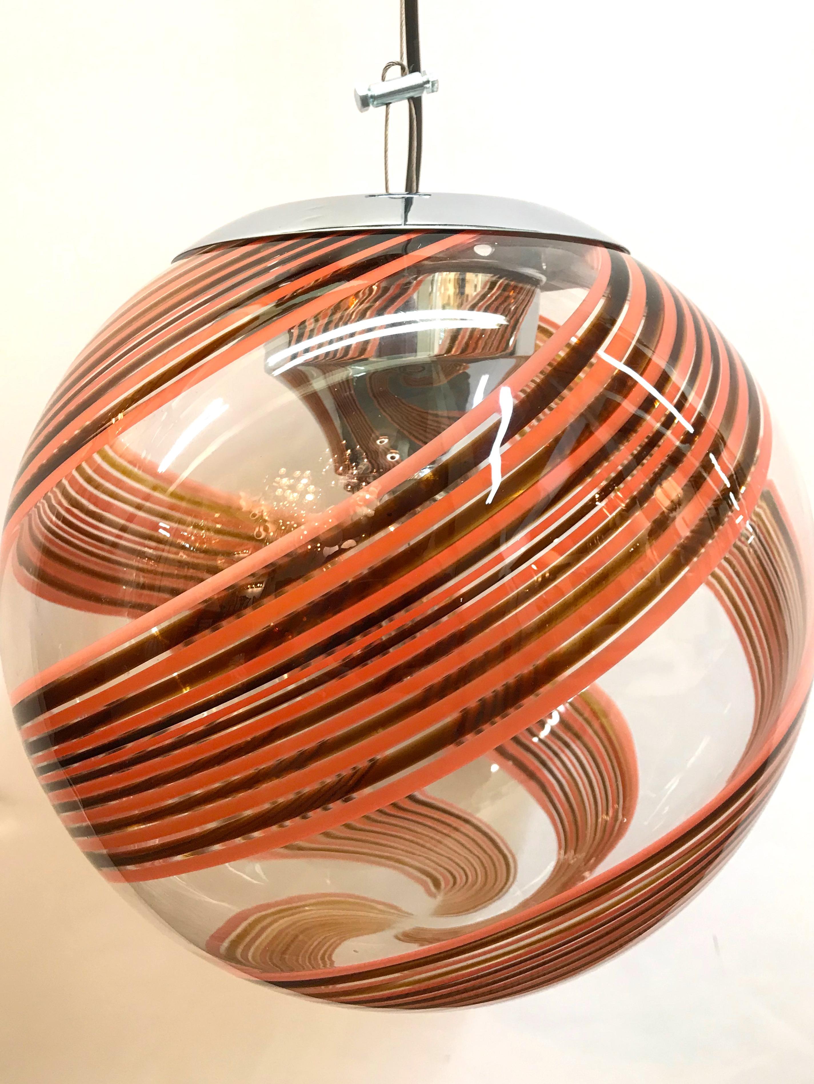 Eine wunderschön mundgeblasene Kugel aus klarem Glas mit schokoladenbraunem und errötetem Streifendiffusor als Pendelleuchte, um 1970. Original stilisierte Chromhalterung und kuppelförmiger Deckenbaldachin. Der Anhänger ist an einem Stahlseil