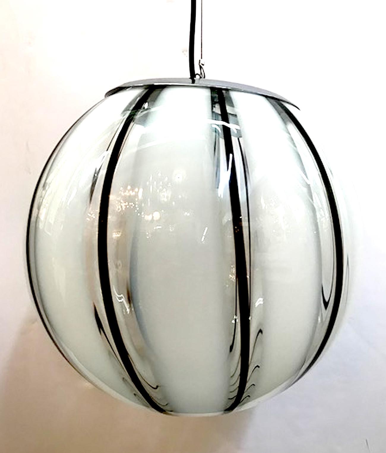 A beautifully handblown, Murano, Italy clear with narrow black and wide white stripe glass globe shade pendant light, circa 1970. Original chrome mounts and ceiling canopy. The pendant is suspended on steel cord with black electrical cord next to