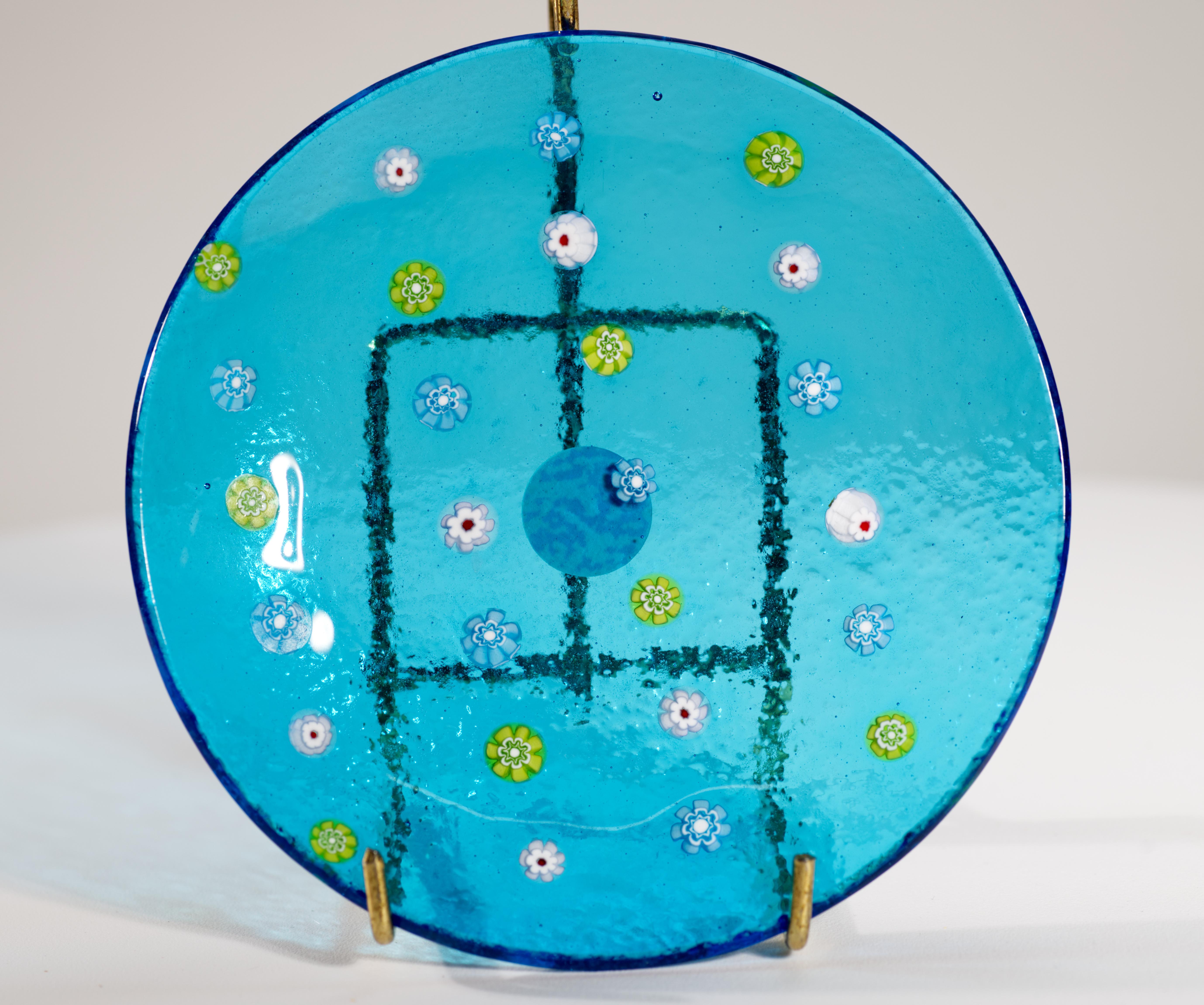  Il vassoio o ciotola in vetro artistico soffiato a mano di Murano vintage presenta 4 file di diversi elementi millefiori nei colori bianco, verde chiaro e blu chiaro su uno sfondo blu acqua. La palette di colori armoniosa e delicata aggiunge