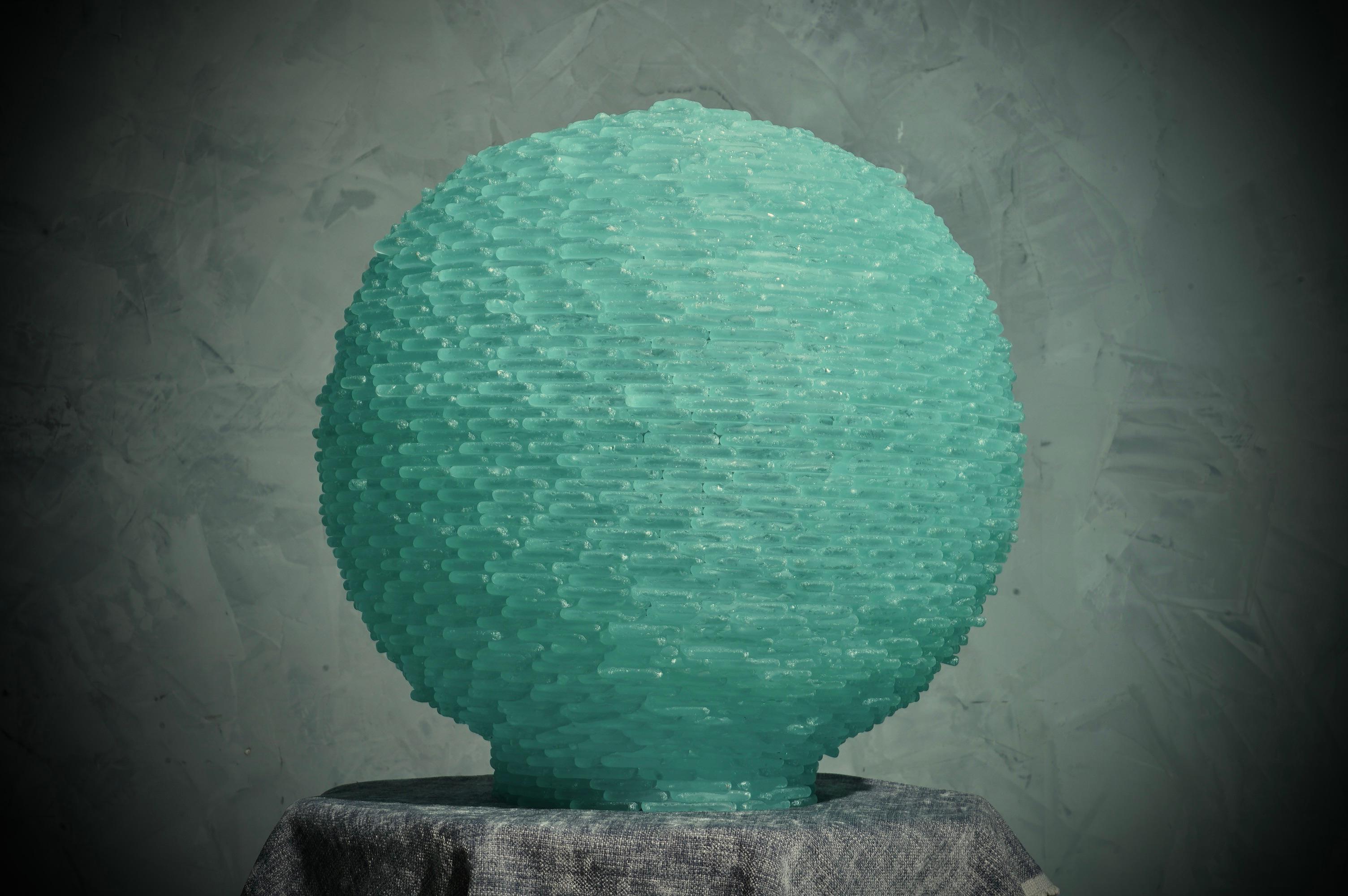Splendide globe terrestre tout en pierres de verre de Murano satinées, belle couleur vert d'eau.

Le globe est composé de deux demi-sphères superposées, formées par une série infinie de petites plaques en verre de Murano. Des lumières internes