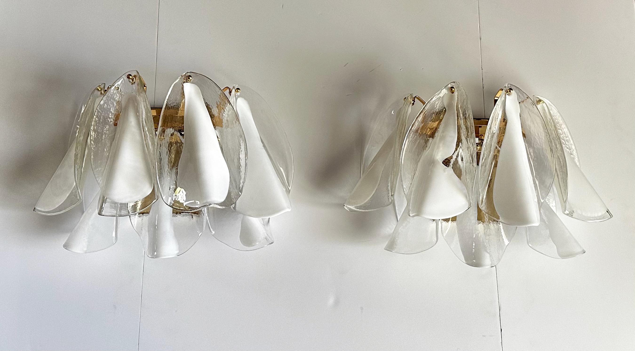 Pair of Murano Mazzega clear and white glass peddle shape sconces supported on brass finish backplates. Each sconce has 7 total glass leaves or peddles, top 4 are slightly larger than the lower 3 peddles. Each sconce uses 2 candelabra size bulb.