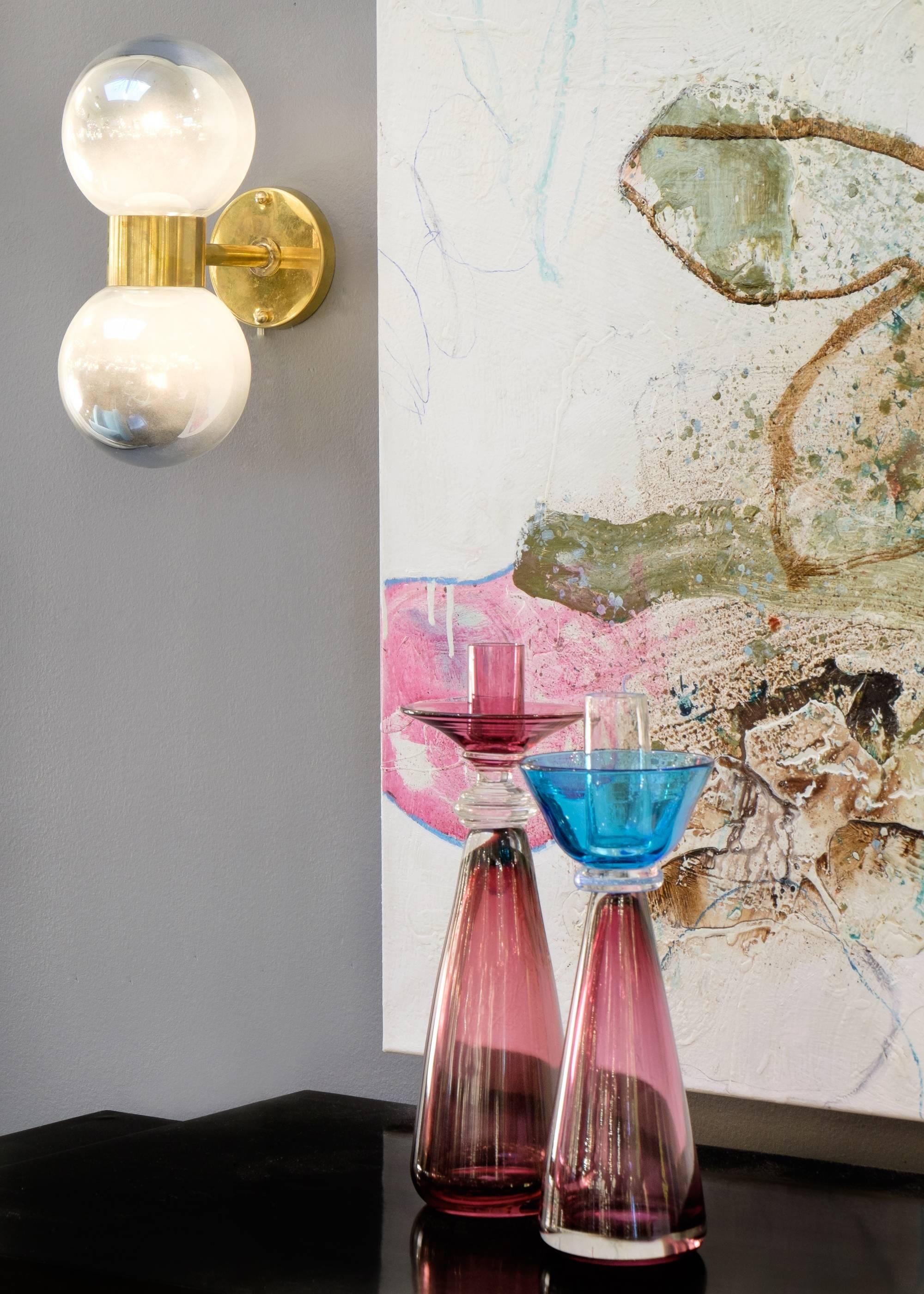 A pair of hand-blown murano mercury globe sconces that softly illuminate and give a modern nod to late Mid-Century chic. Comprised of two Murano mercury glass globes with a brass accent separating both. A beautiful piece that is equally as stunning