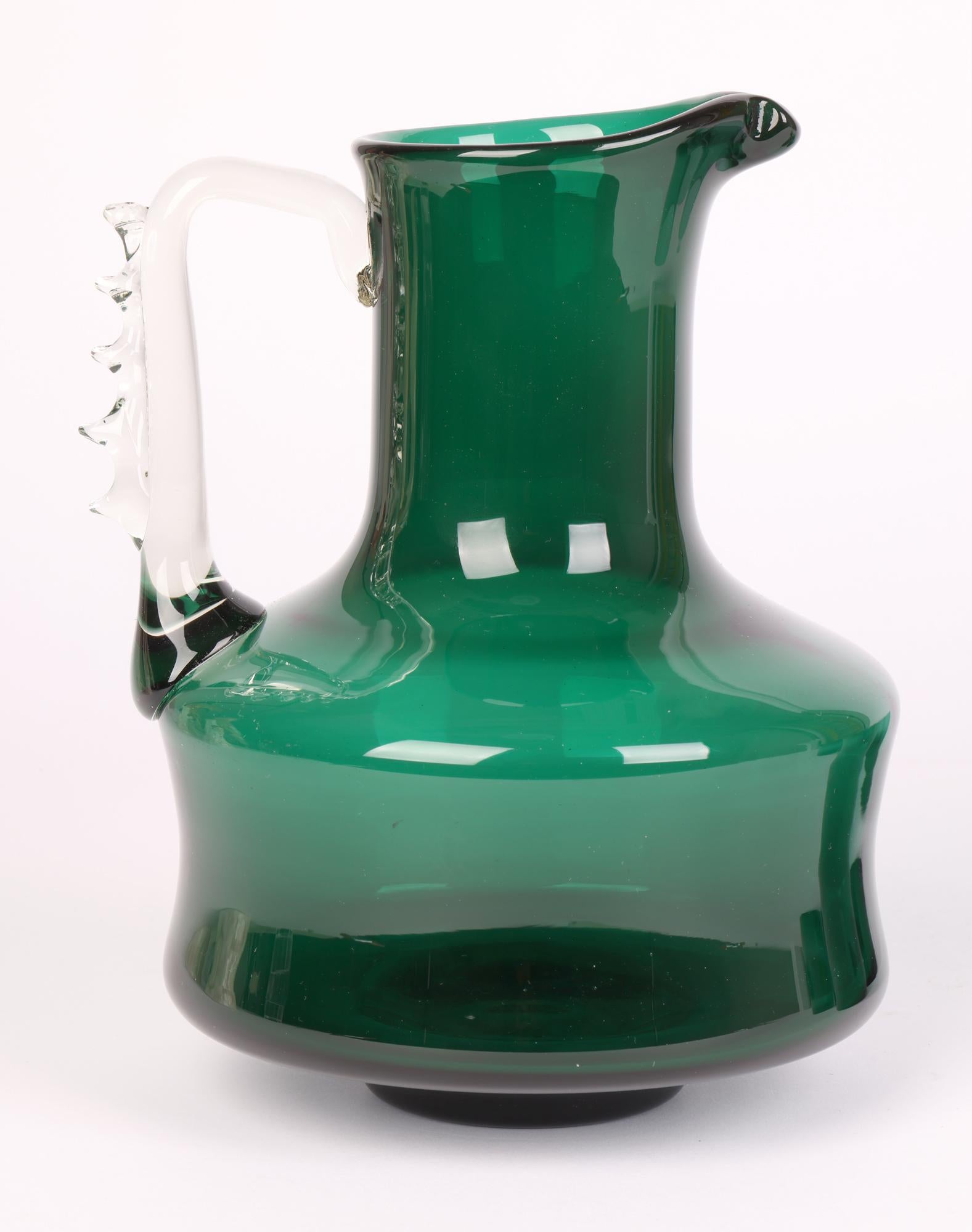 A stylish Italian Murano mid-century green glass lemonade set comprising of a jug and five tumbler glasses dating from around 1960. The jug stands raised on a narrow round foot with a wide pinched body and tall funnel shaped neck with a pinched