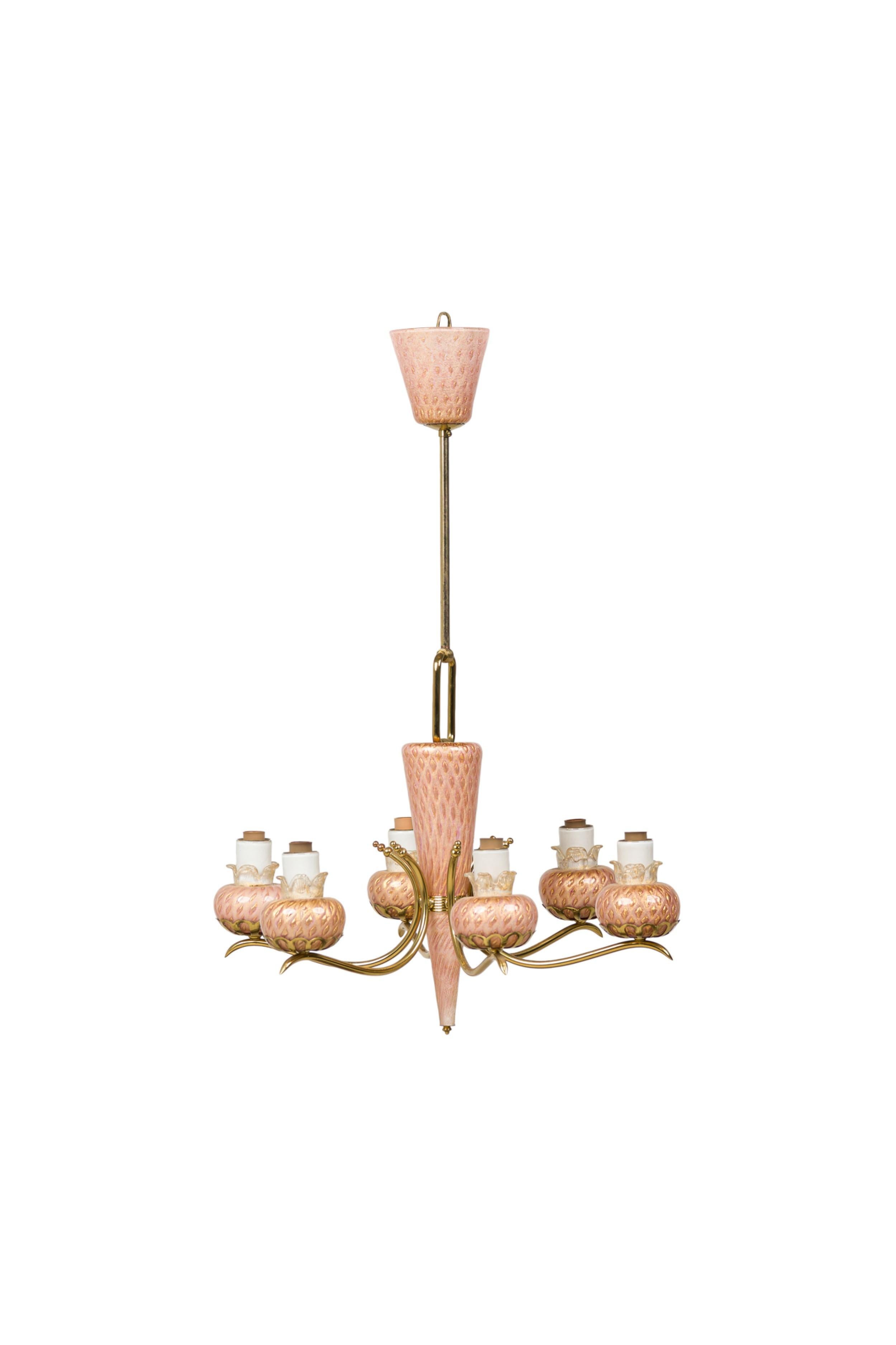 Mid-Century Italian brass chandelier featuring a pink glass upturned cup finial with a gold flecked diamond pattern, downturned conical base and 6 scroll arms with blossom-form lamp holders. (MURANO)
 

 Needs rewiring
