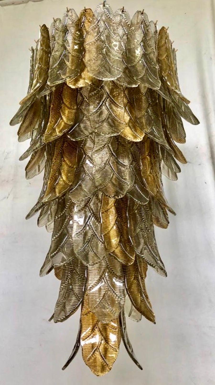 Ein Aufruhr von Blättern, mit einer eleganten Doppelfarbe aus Gold und Rauch. Raffinesse und Klasse im Murano-Stil, einzigartige Stücke, die immer wertvoll bleiben.

Goldfarbene Eisenstruktur mit Blättern aus Murano-Glas rundherum, in zwei Farben.
