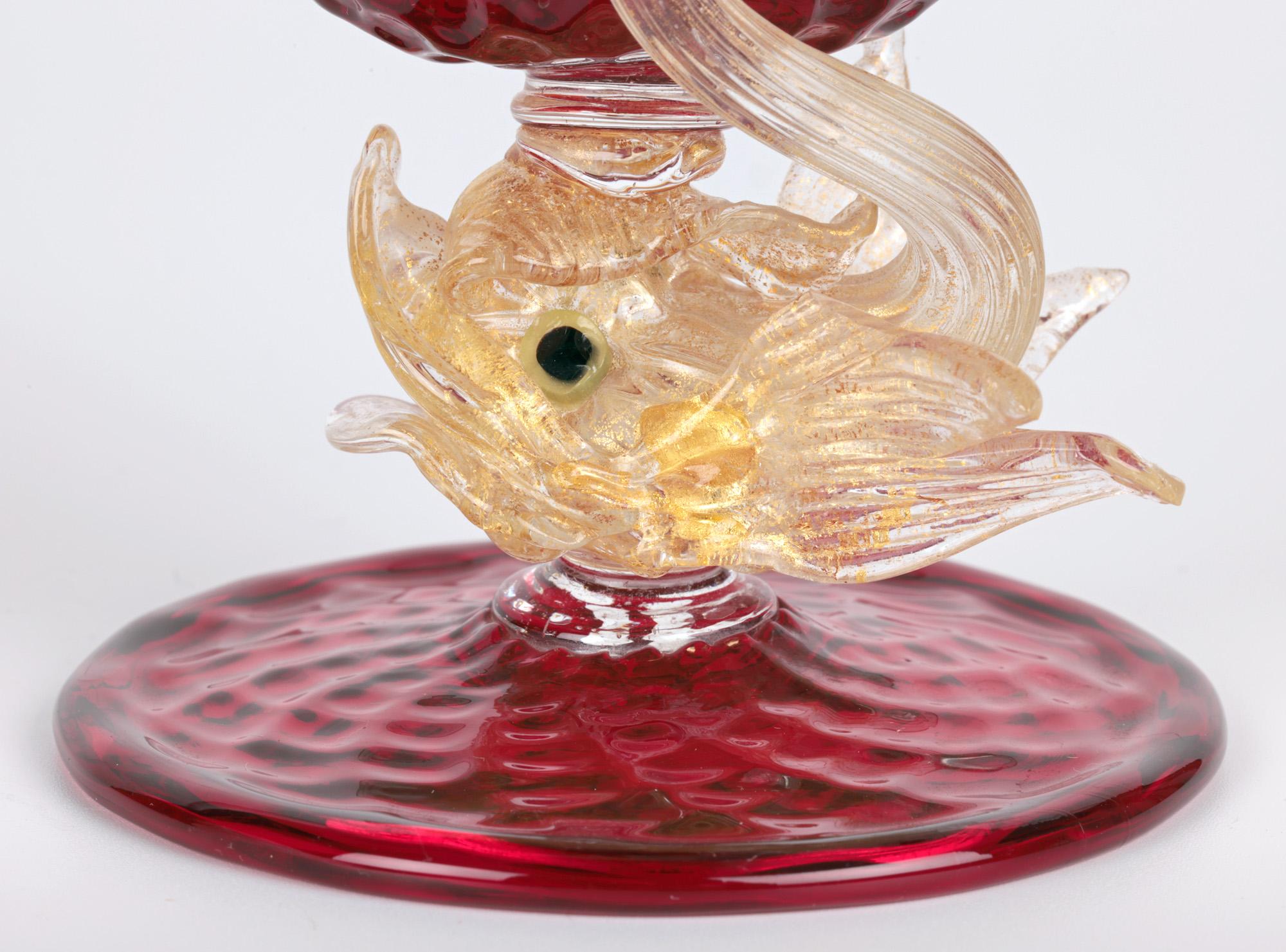 A stunning Italian Venetian mid-century ruby glass dolphin stem bowl made on Murano. The bowl stands raised on a wide round texture molded foot with a folded edge rim with a centrally mounted dolphin stem with a raised tail supporting a fan shaped