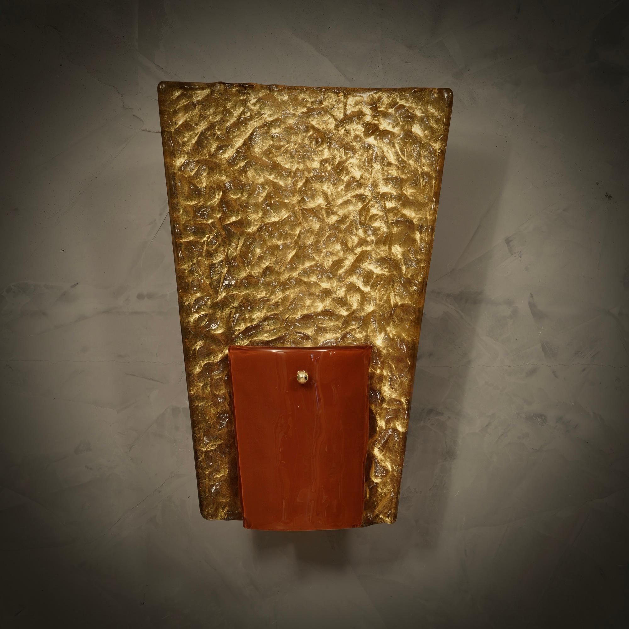 Elegant and rich in design, this applique recalls the old style of Murano, when shapes and external appearance were the most important things.

The applique is round in shape and consists of a brass arm surmounted by two Murano glasses, a larger one