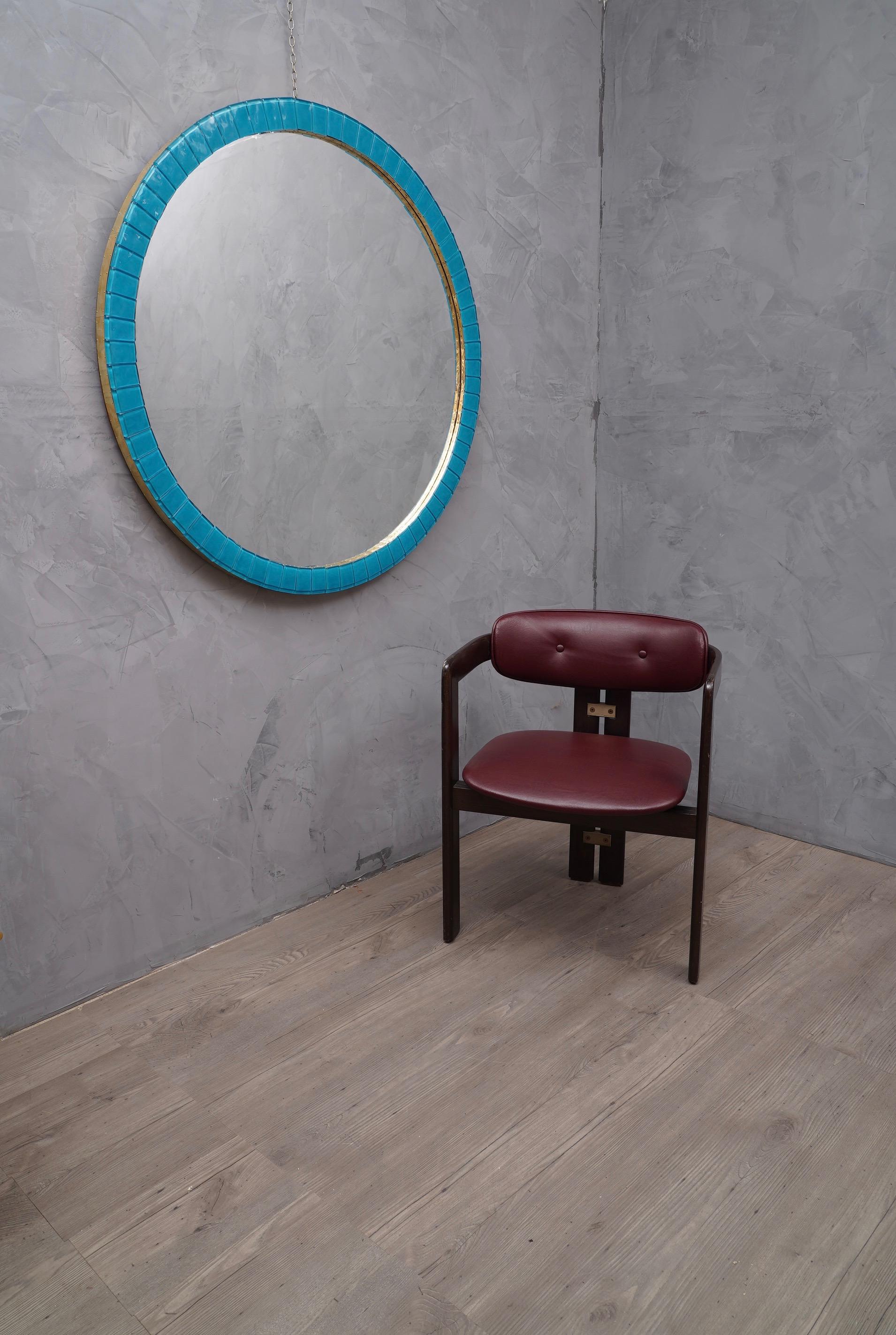 Very elegant mirror of electric blue color, the frame is very fine and precious also for the contribution of brass.

The structure of the frame is in wood round in shape, above are applied small bricks in blue Murano glass. Along the two lateral