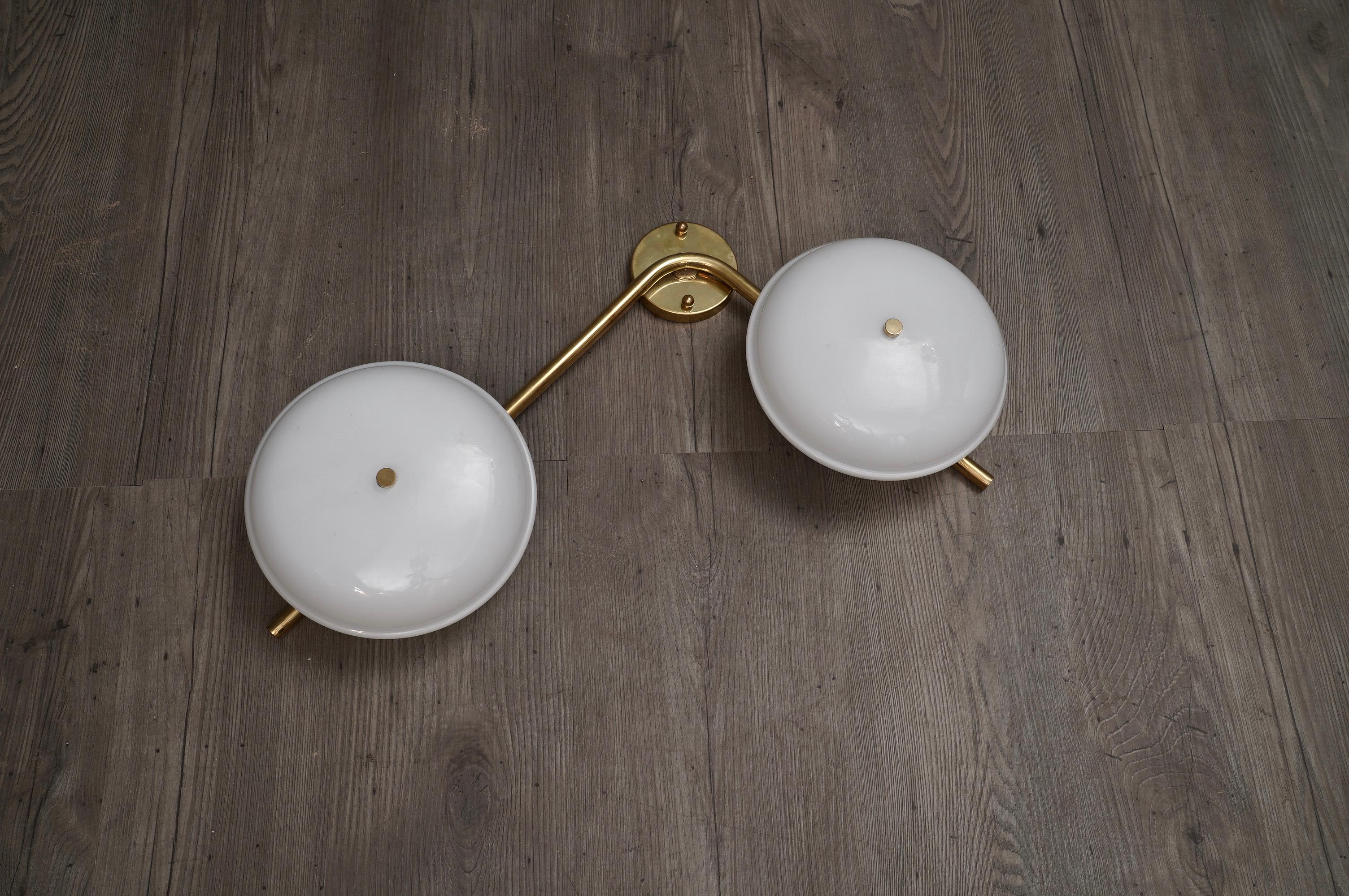 Linear and simple these wall lamps in white Murano glass. A light brass tube combines two white Murano glass globes.

Composed of a brass structure, to which two globes in white glass are joined. Simple but impressive, very bright. As you can see