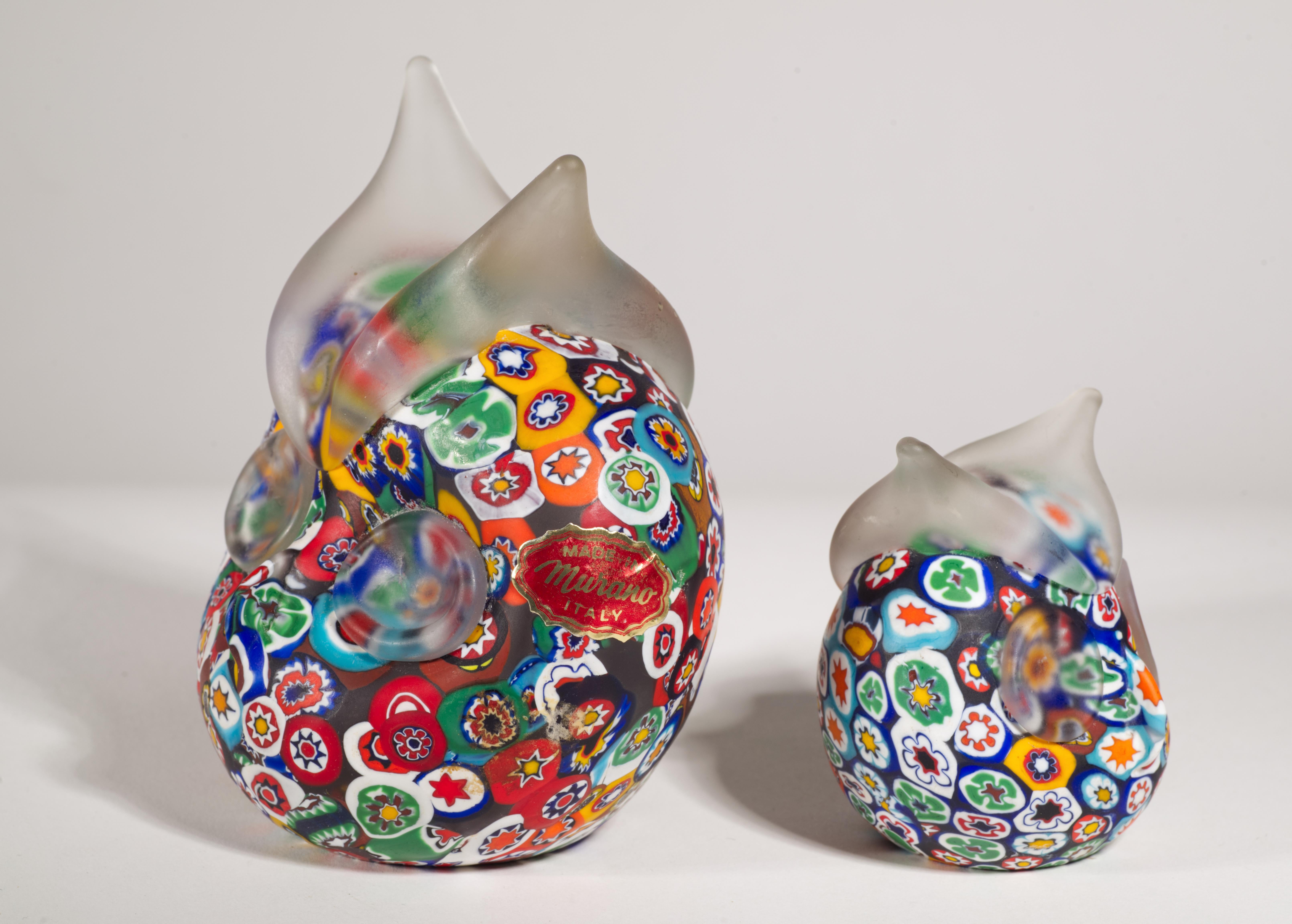  An unusual owl shaped paperweights feature colorful millefiori on dark background and an applied clear glass eyes and ears details, finished with matte surface. 

The larger owl is marked with the original 