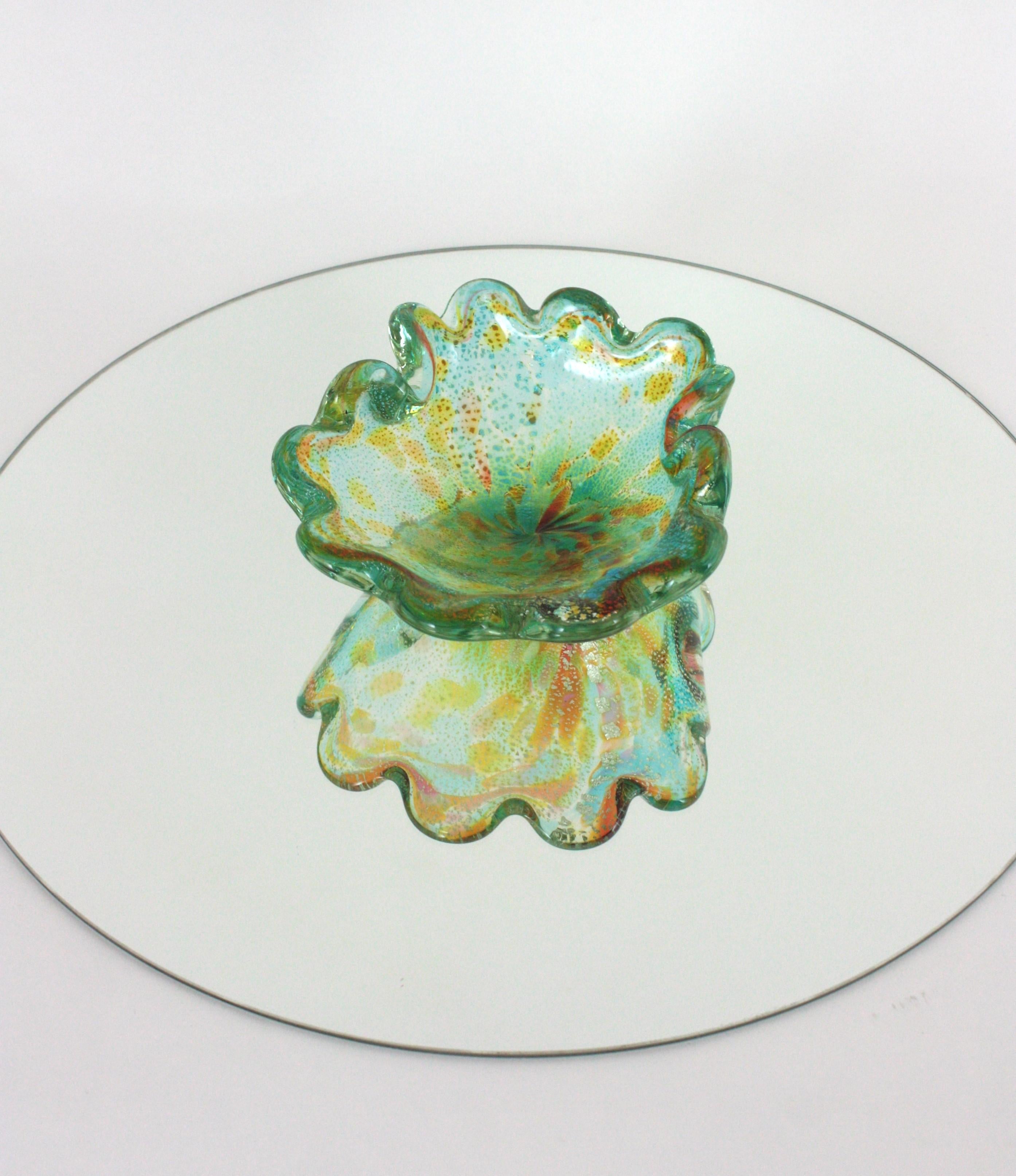 Schale aus mundgeblasenem Murano-Kunstglas mit Wellenschliff und Silberflecken
Auffällige, muschelförmige Murano-Kunstglasschale oder Aschenbecher in grün-blauen Farbtönen mit Murrinendekoration und braunen, bernsteinfarbenen und gelben Tiermotiven