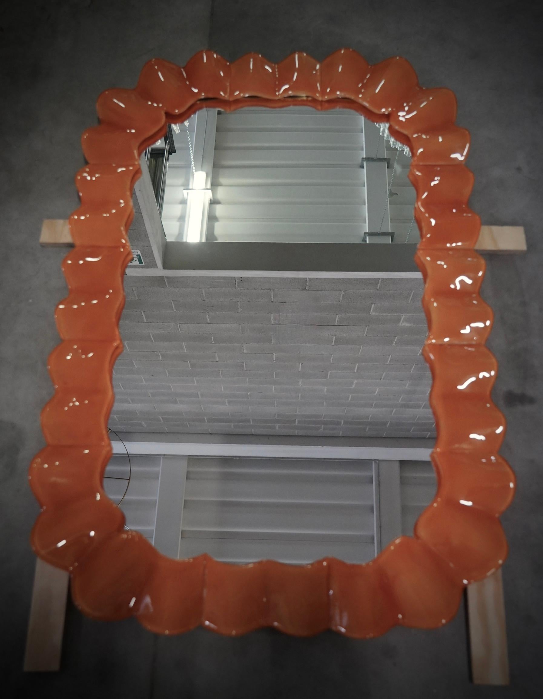 Prächtiger Spiegel aus leuchtend orangefarbenem Murano-Glas. Ein Spiegel, der allein Ihr Zuhause einrichtet. Der reiche, aber geschmackvolle Spiegel hat ein ganz besonderes Design, mit einer sehr schönen Form dieser Glasteile.

Der Spiegel hat eine