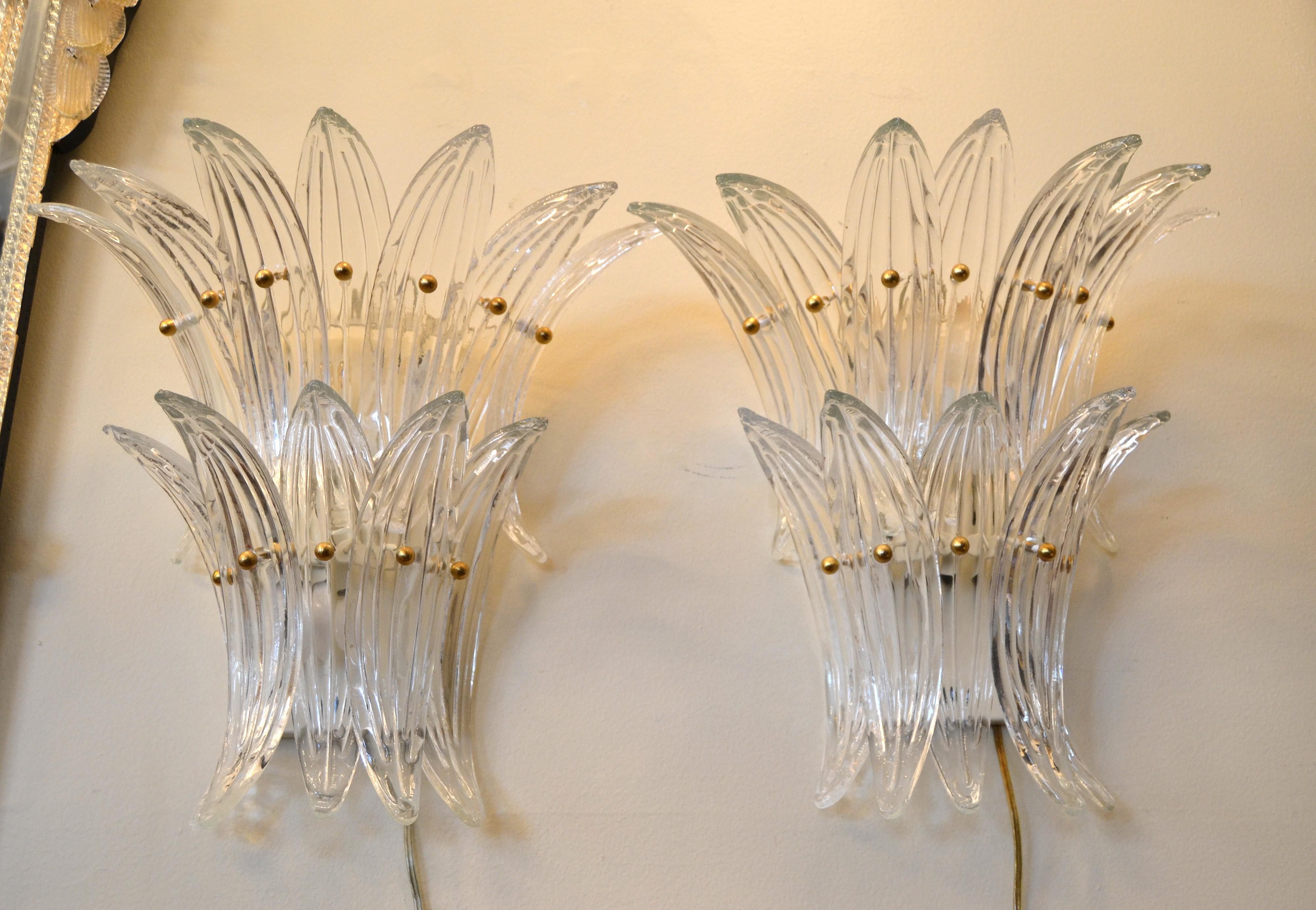 A pair of murano blown glass ornaments sconces which resembles the fan-shaped leaves of a palm tree, made in Italy.
The glass leaves are mounted on a metal frame and fastened with round brass screws.
Each sconce has 12 glass ornaments and uses 3