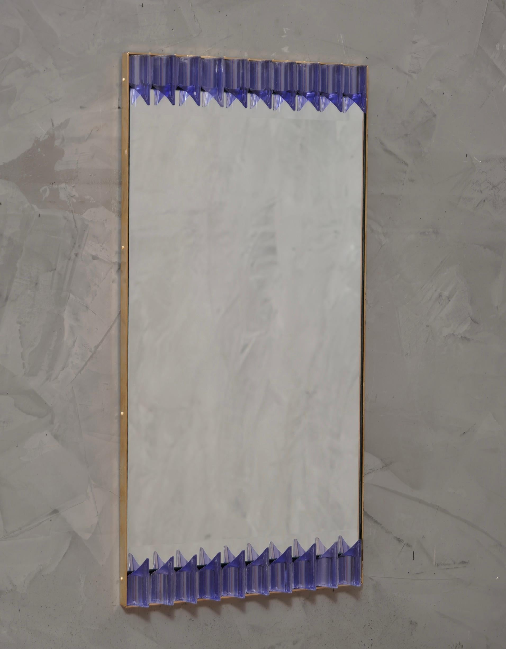 Una robusta cornice color pervinca raggiunge l'occhio di chi guarda, lasciandolo incantato; specchio da parete in vetro artistico di Murano color pervinca. Di forma splendida e di dimensioni eccellenti, lo specchio da parete è un vero e proprio