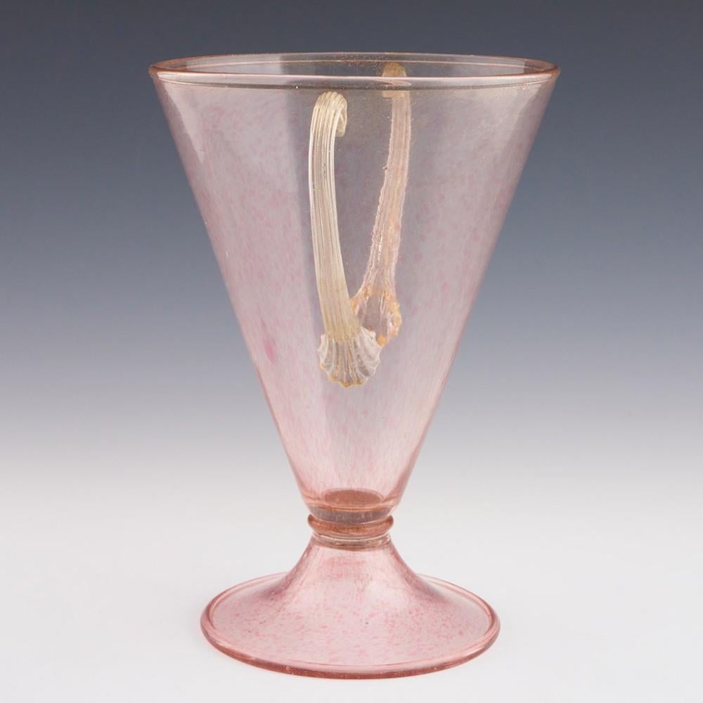 Heading : Murano glass vase
Date : c1925
Origin : Murano
Bowl Features : Pink 'a macchie' speckled and eventurine conical glass with applied reeded handles. Conical folded foot
Marks : None
Type : Lead free
Size : 27.2cm height, 19cm