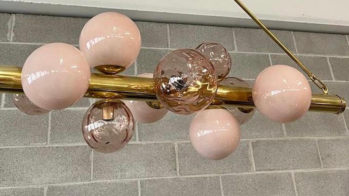 Characterized by simplicity and linearity Murano chandelier, its beautiful colors with more shades of pink color.

The chandelier is composed of a large brass section tube, which acts as a supporting structure; ten Murano glass spheres of two