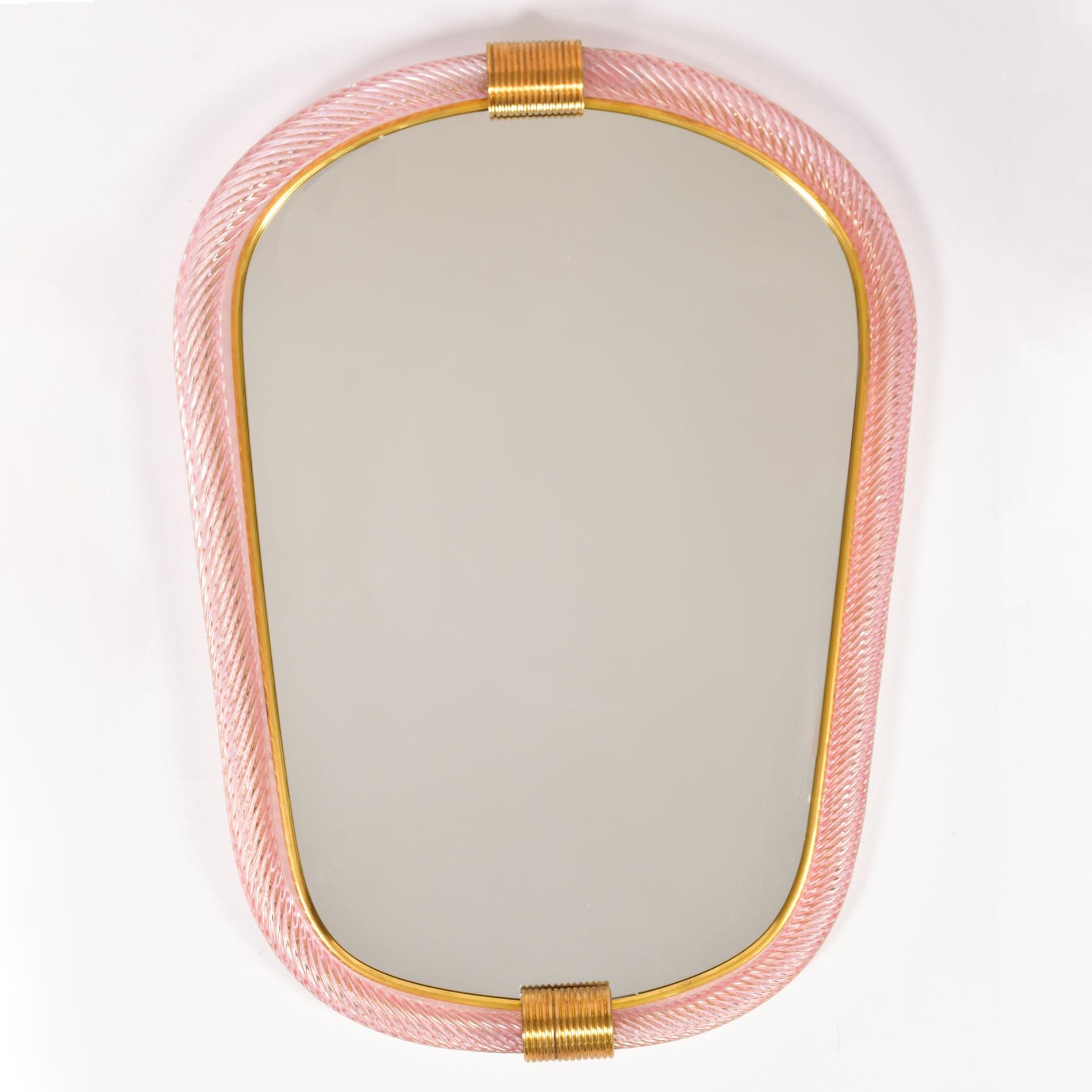 Miroir eliptique en verre de Murano soufflé à la main, rose pâle et moucheté d'or, avec deux fermoirs cannelés en laiton en haut et en bas, le bord intérieur bordé d'un mince filet en laiton.

Également disponible en bleu pâle.

Délai de 8 à 9