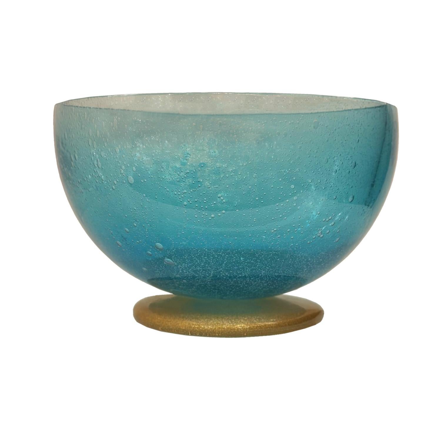L'élégance simple définit ce bol à pied magnifiquement travaillé. Le verre Pulegoso de Murano, d'une couleur turquoise translucide, offre un contraste saisissant avec les inclusions dorées scintillantes de la base. Qu'il s'agisse de décorer la table