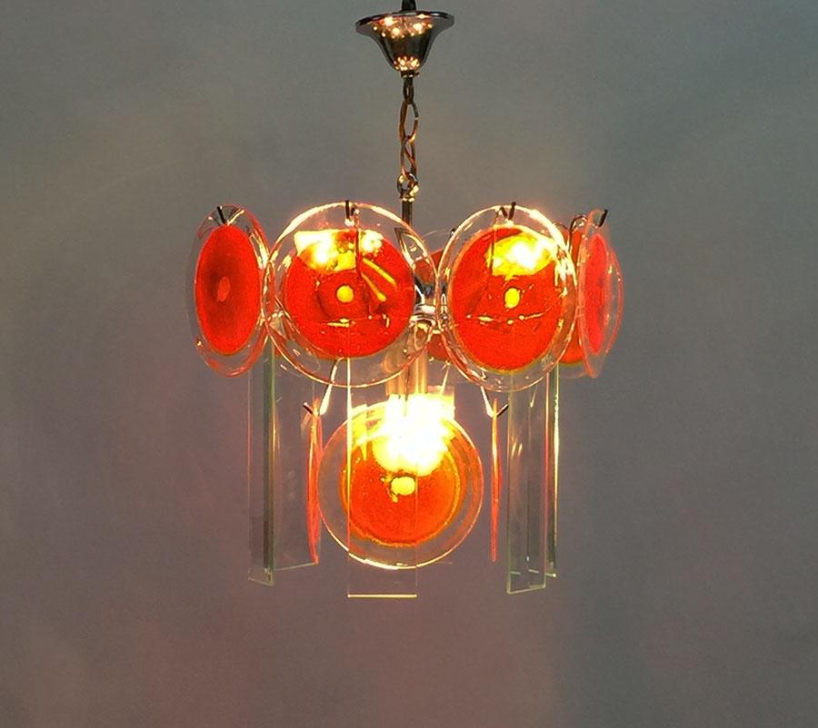 Murano red disc chandelier by Gino Vistosi

Murano disc chandelier designed by Gino Vistosi, Italy, 1970s
12 Red Murano glass discs and 6 rectangular facet cut discs. 
8 Discs with red and a yellow stripe and 4 single red. 
6 rectangular discs,