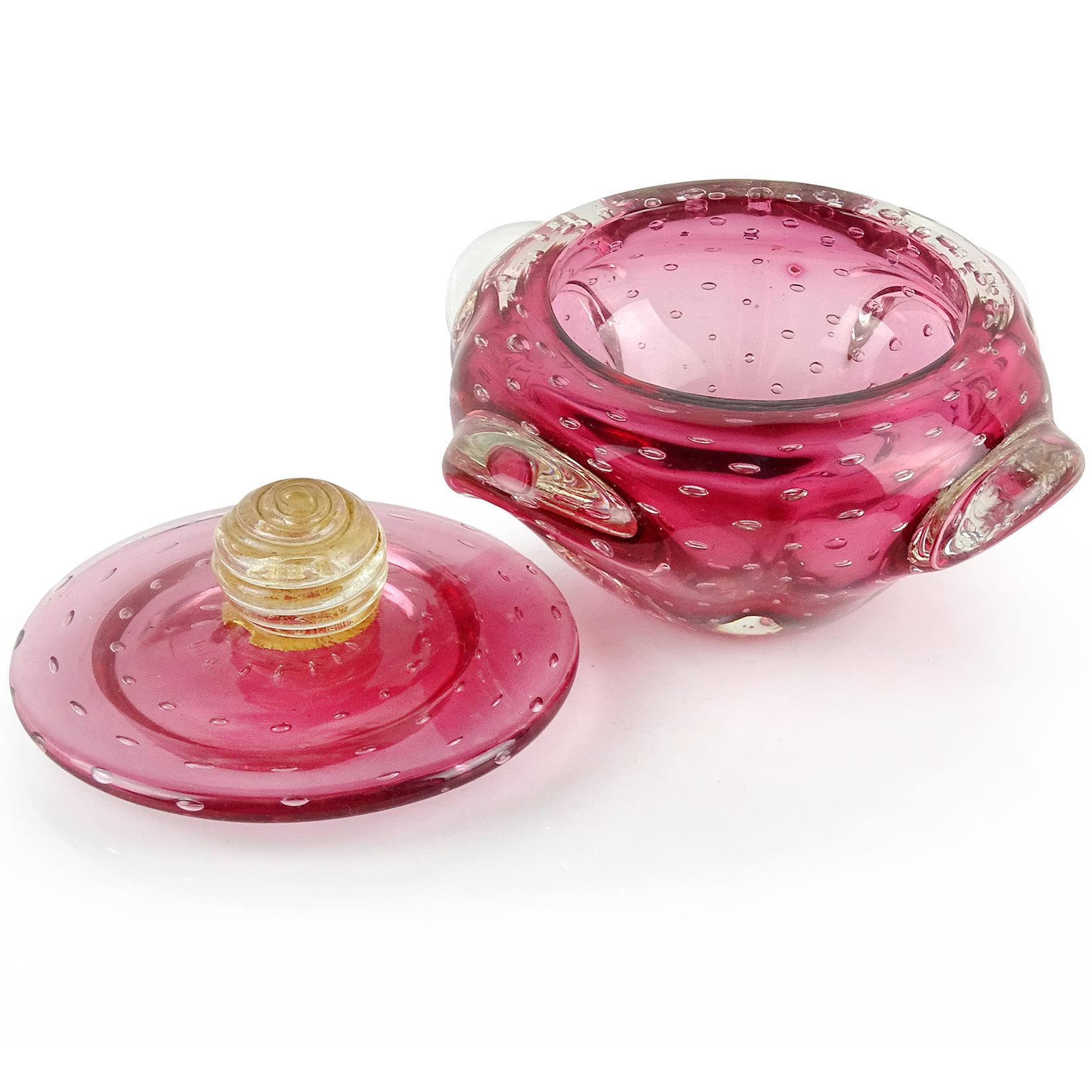 Beautiful vintage Murano hand blown transparent reddish pink and controlled bubbles Italian art glass powder or jewelry box. The lidded jar has pulled glass on the sides, with a swirled gold leaf ball at the top of the lid. Great decorative piece