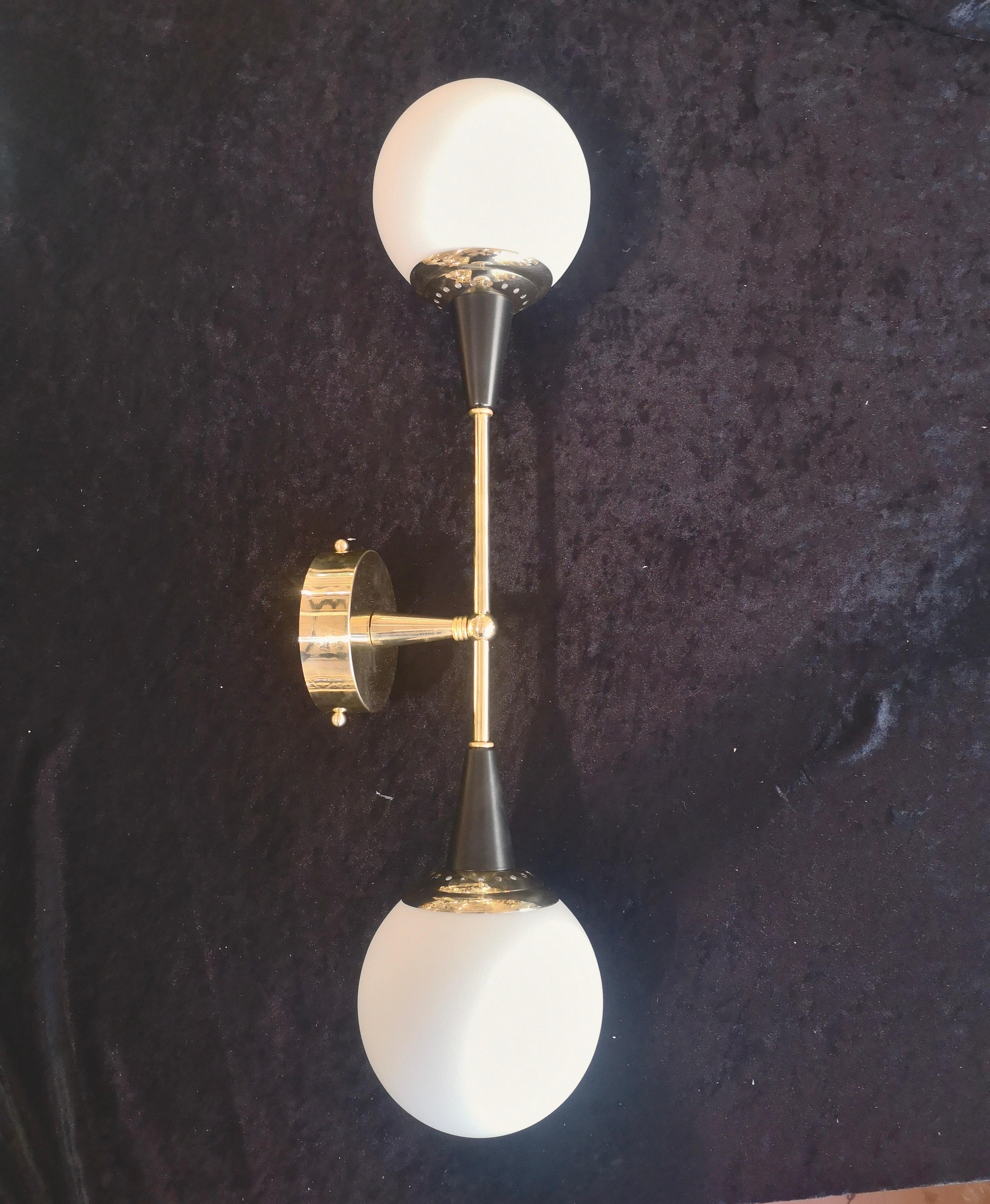Refined and delicate design for this wall light with white Murano glass.

The applique are formed by a brass structure that allows the superimposed housing of two beautiful white Murano glass spheres. The design is very clean and simple, but at the