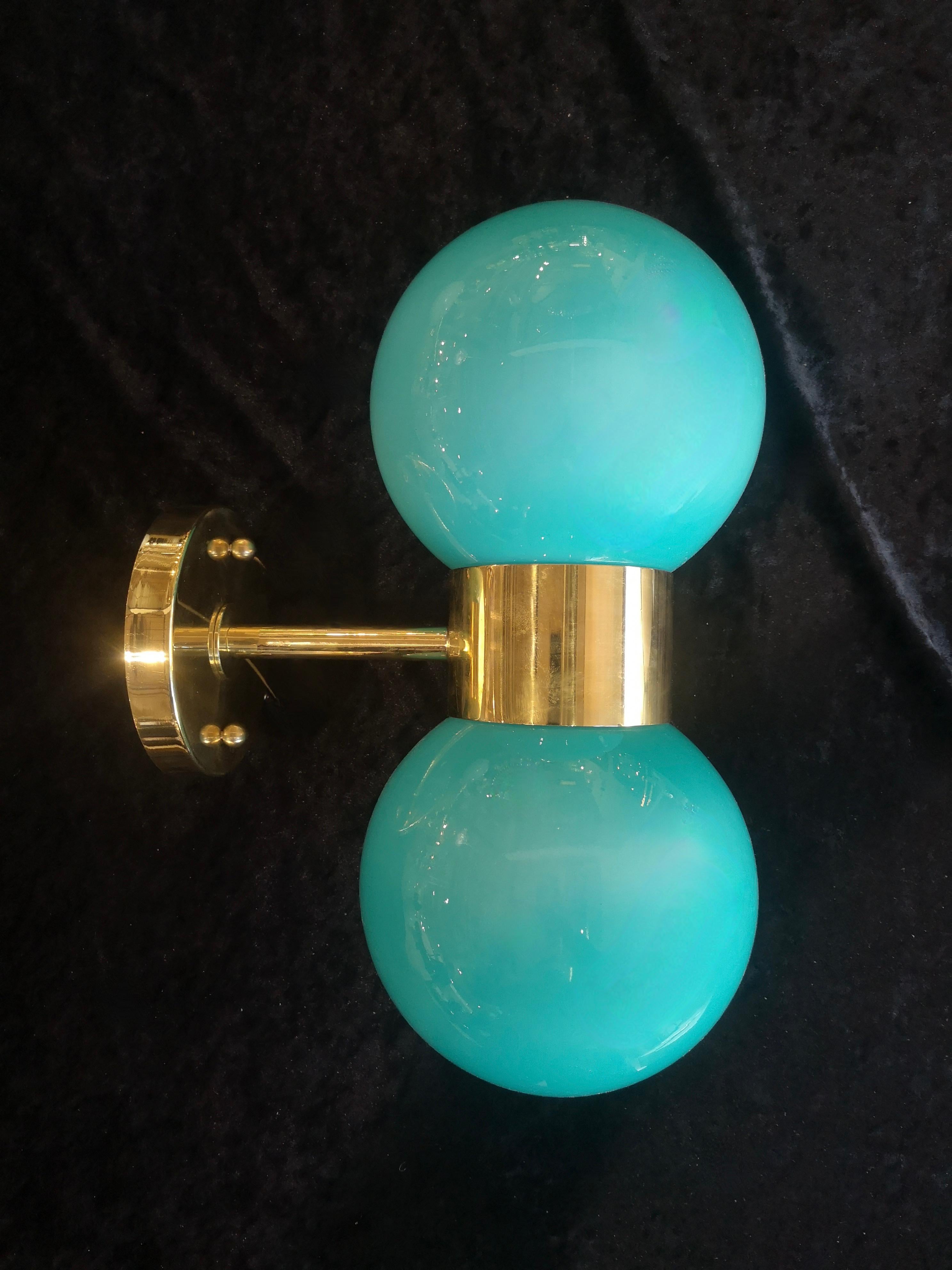 Refined and delicate design for this wall light with green Murano glass.

The applique is formed by a brass structure that allows the superimposed housing of two beautiful emerald green Murano glass spheres. The design is very clean and simple, but