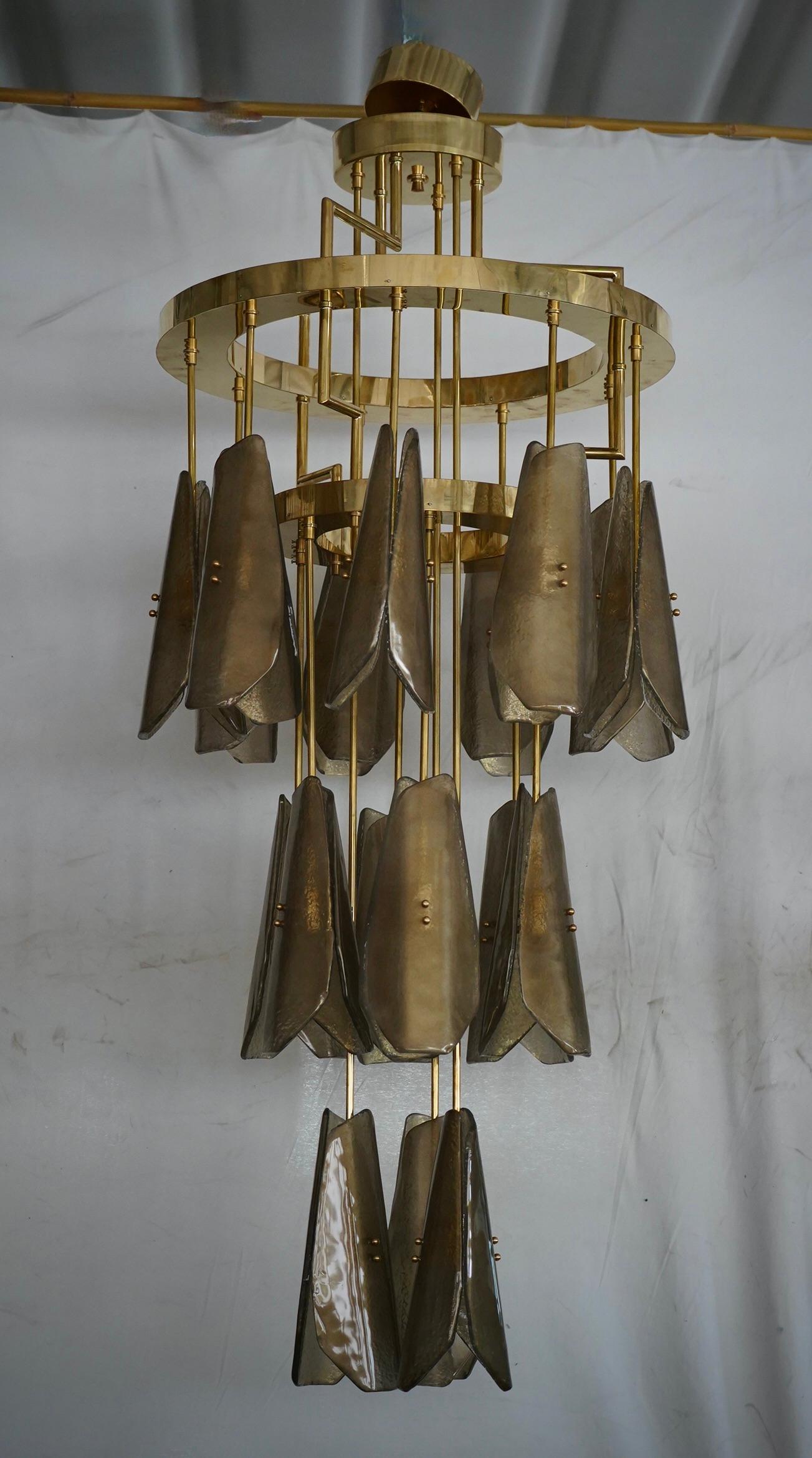 Una elegante lámpara de cristal de Murano de líneas sinuosas, de forma muy sencilla y lineal, pero increíblemente bella. Esta elegancia también se debe a la exquisita artesanía de las baldosas de vidrio. El refinamiento y la clase, típicos del