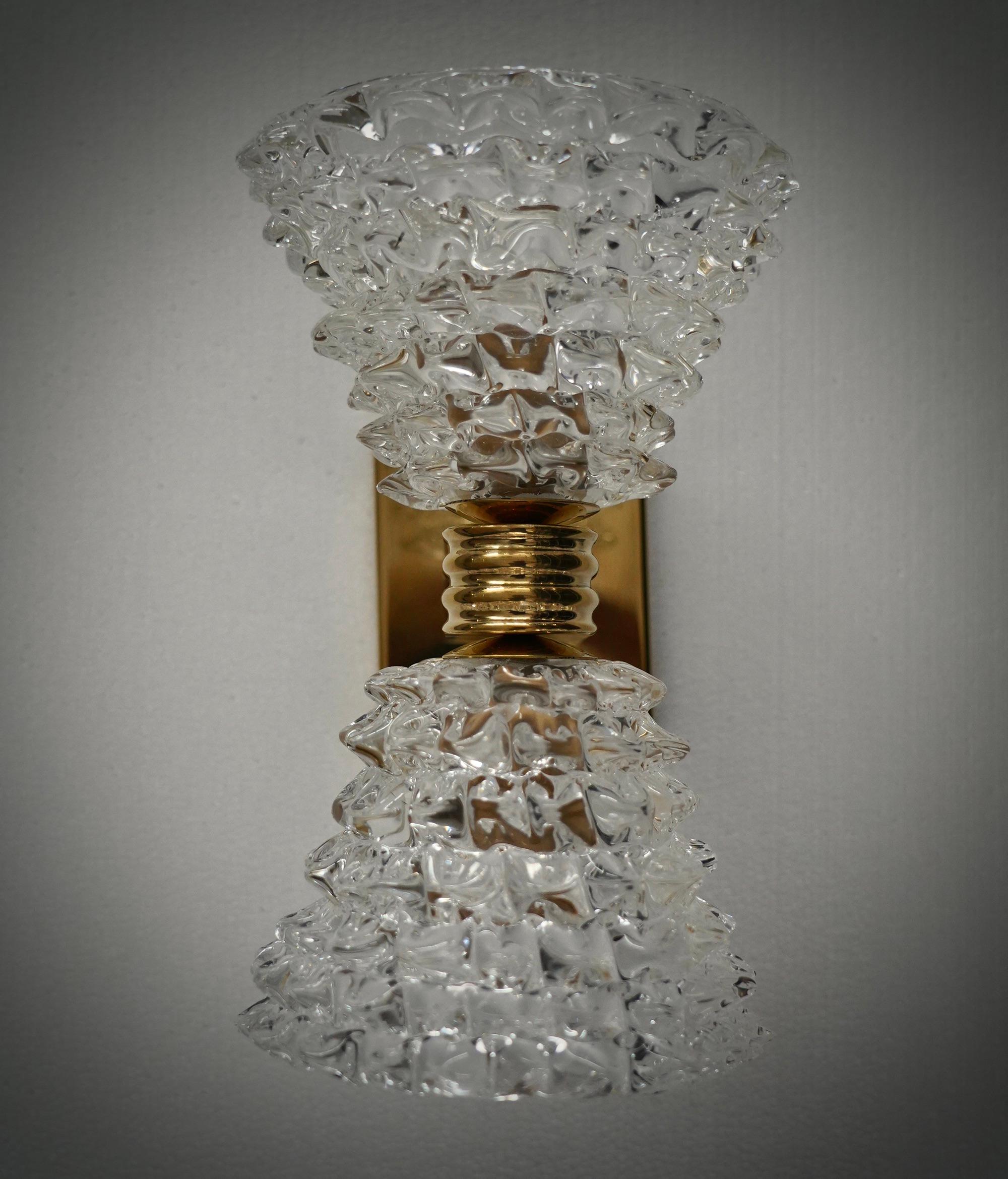 Design raffiné et délicat pour cette applique transparente en verre de Murano.

L'applique se compose d'une structure en laiton qui permet de loger une belle double vasque en verre transparent de Murano. Le design est très épuré et simple, mais