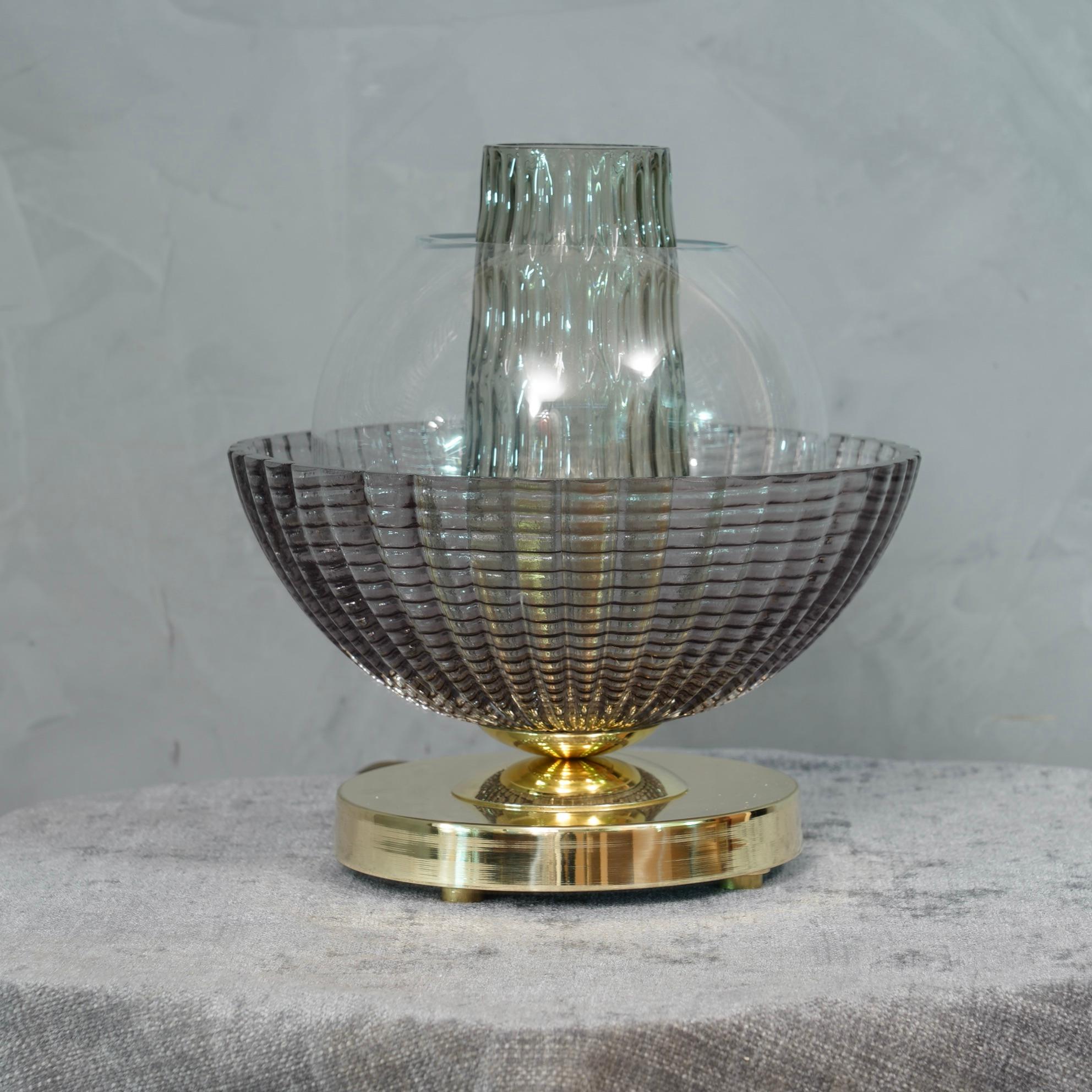 A very special and original Murano table lamps, a series of round glass arranged one on top of the other, in a smoked and brass color. Their shape is fascinating.

The lamp is composed of a round brass base, where cope in Murano glass have been