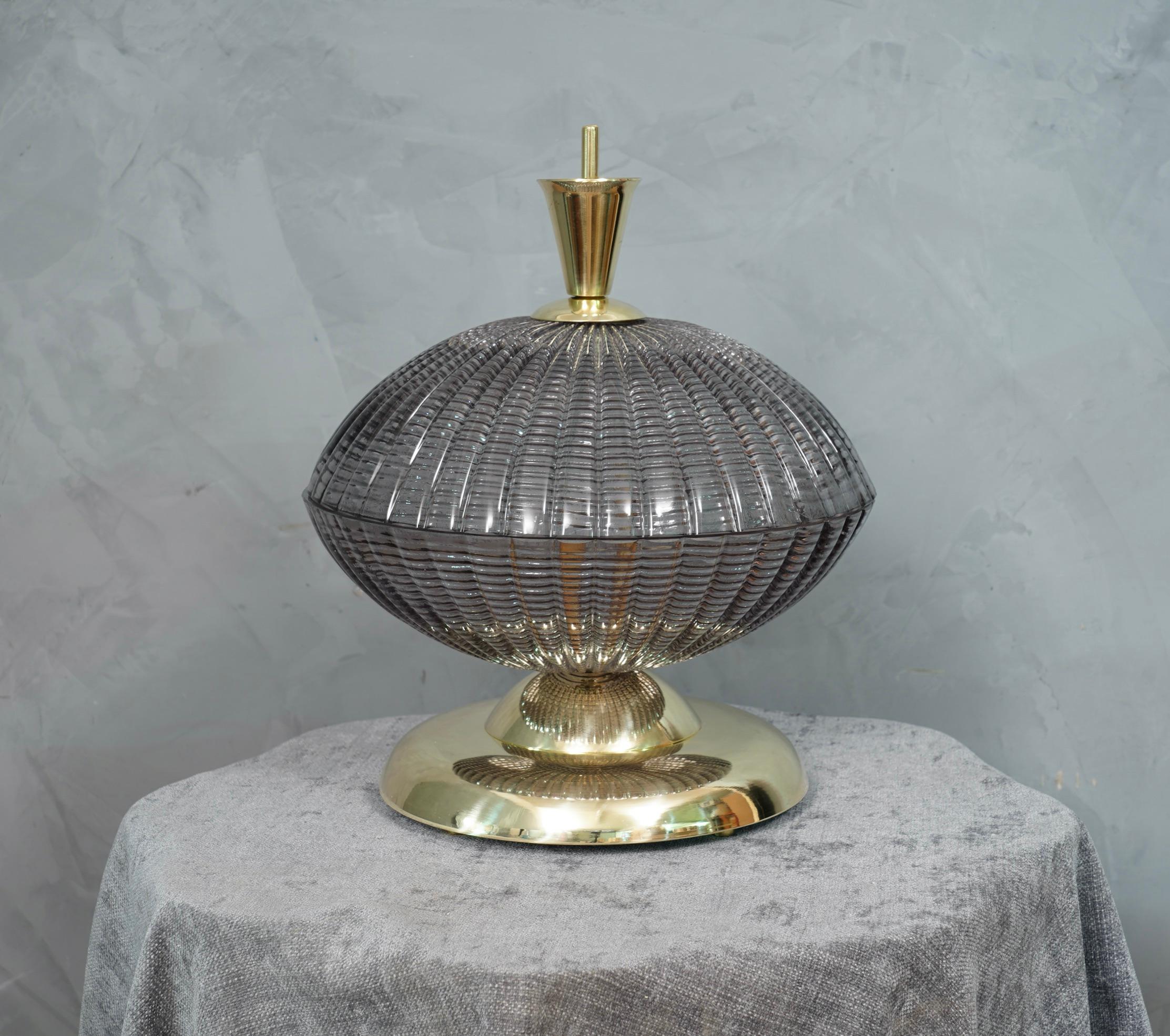 A very special and original Murano table lamps, a series of round glass arranged one on top of the other, in a smoked and brass color. Their shape is fascinating.

The lamp is composed of a round brass base, where cope in Murano glass have been