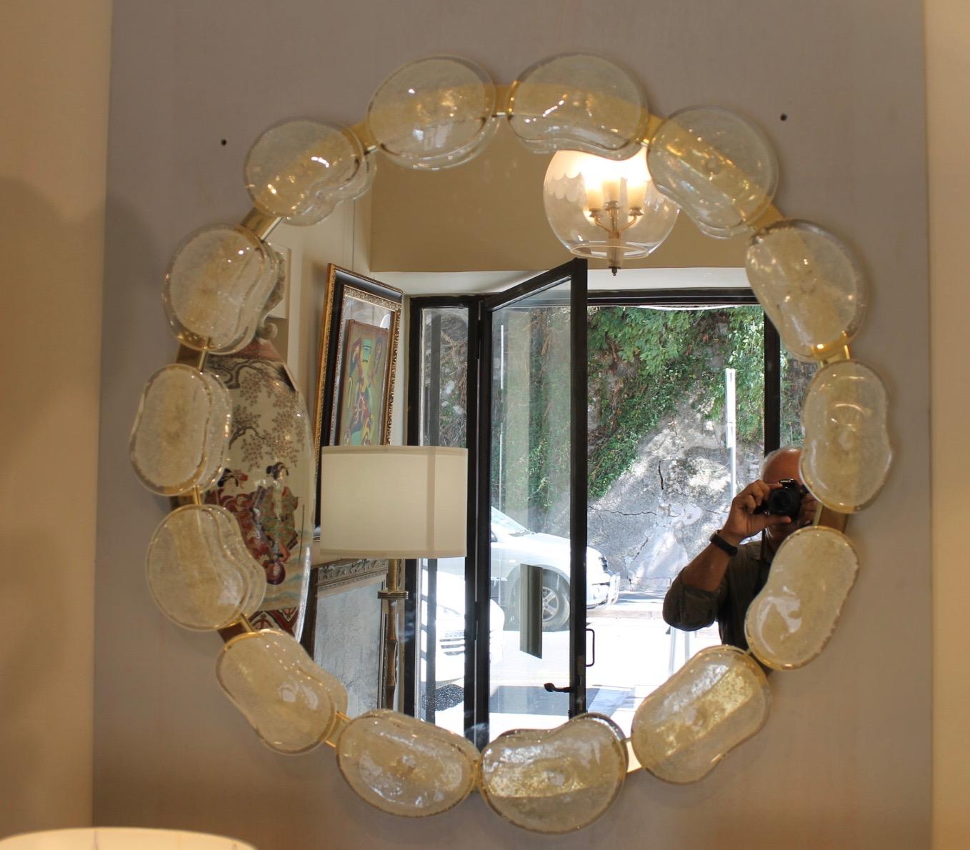 Round mirror surrounded by Murano glass pebbles. The outline of the mirror is in gilded brass.
Creation of a master Murano glassmaker
Mirror that can be placed in an entrance, living room above a piece of furniture.
During transport, the stones come