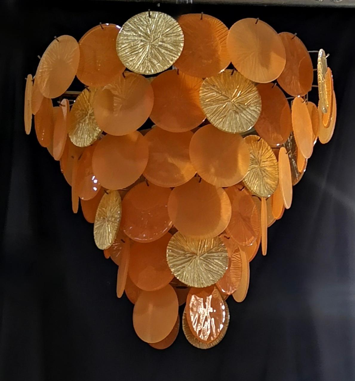 Brilliant Murano chandelier with glass medallions in orange and gold color. 

Composed of an iron structure gold colored, about 120 medallions are hung around it. The chandelier has an inverted pyramid shape with a round base. The chandelier have a