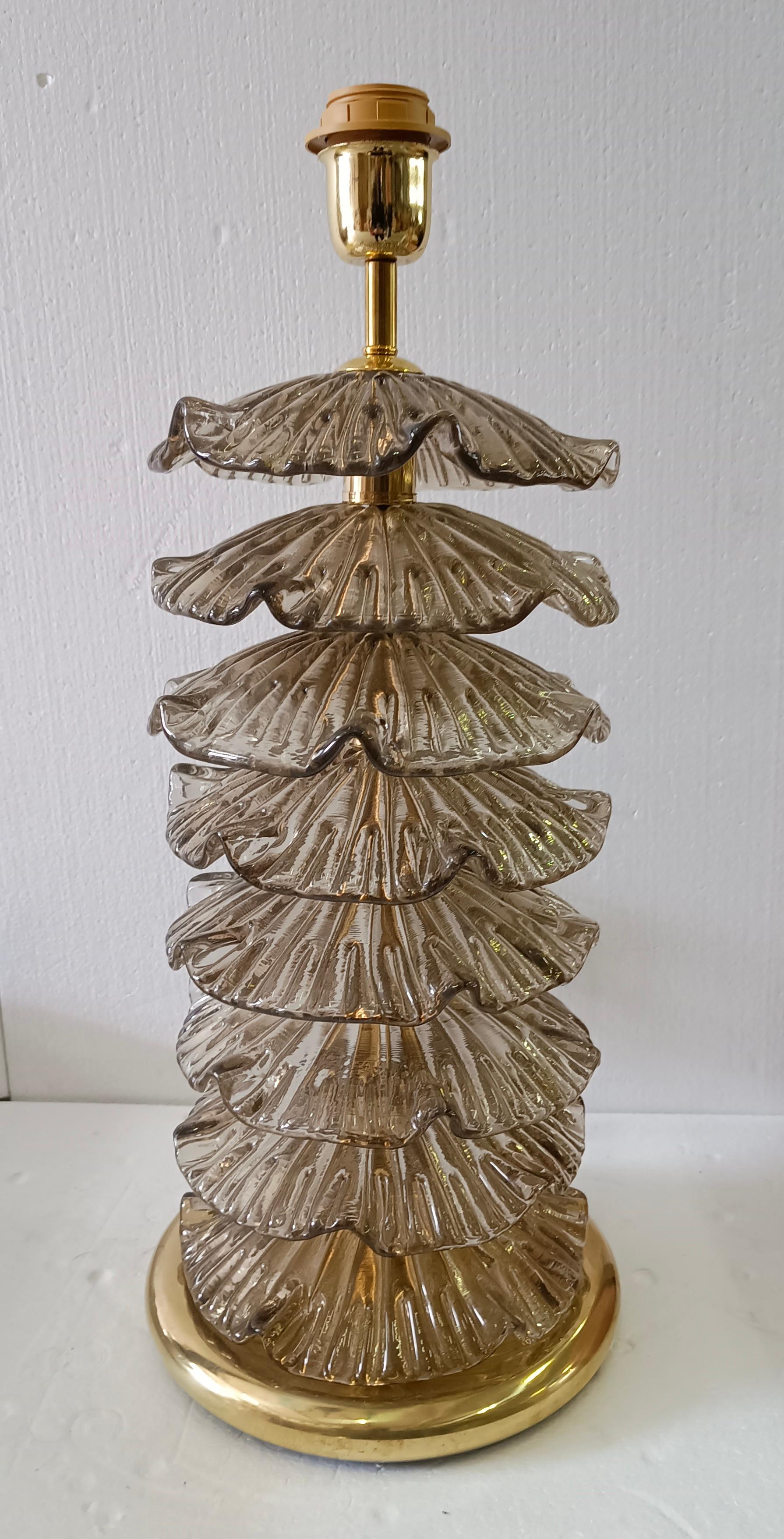 Une lampe très particulière et originale de Murano, une série de feuilles de verre rondes disposées les unes au-dessus des autres, d'une couleur fumée. Leur forme est fascinante.

La lampe est composée d'une base ronde en laiton et d'une tige sur