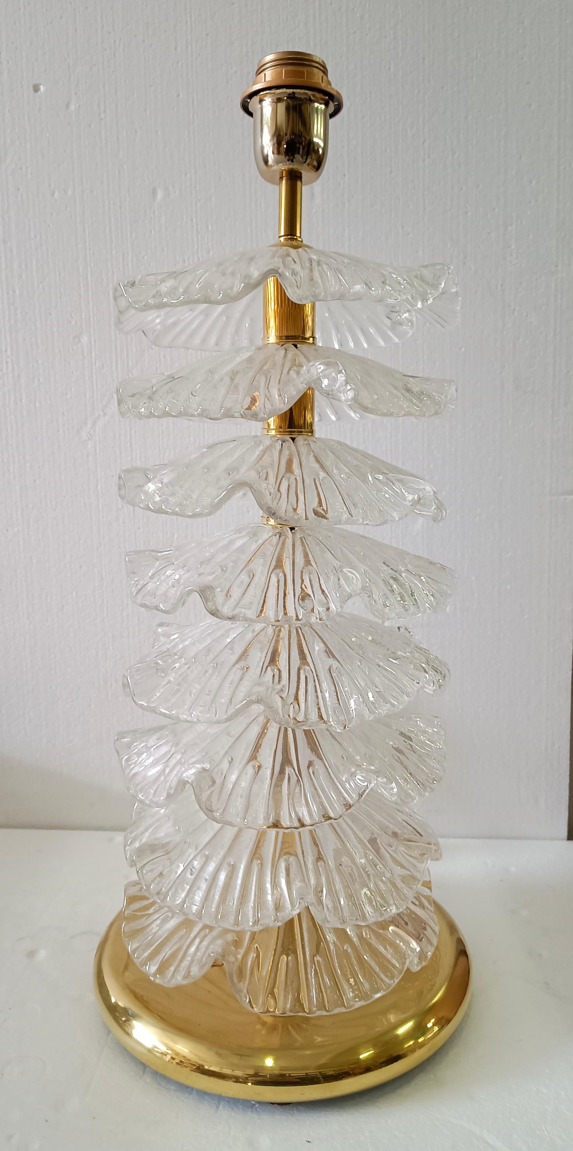A very particular and original Murano lamp, a series of round glass leaves arranged one above the other, of a transparent color. Their shape is fascinating.

The lamp is composed of a round brass base and a stem on which are inserted transparent