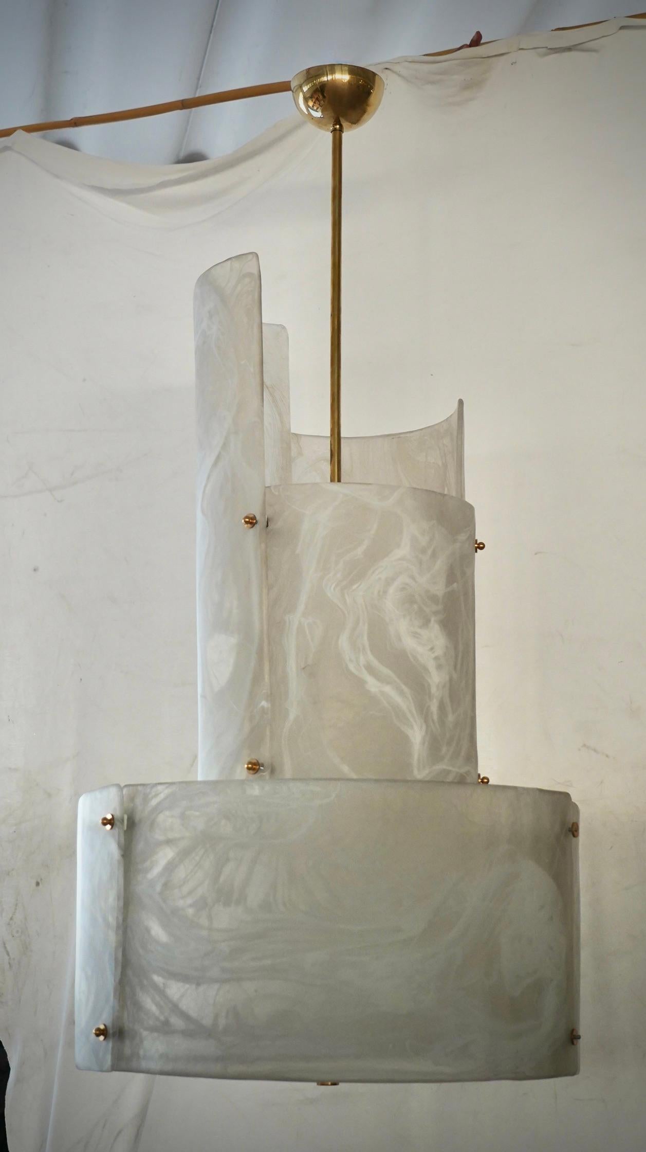 Uno splendido lampadario in un sorprendente colore ghiaccio sabbiato con striature bianche; un cerchio perfetto di lastre di vetro color ghiaccio.

La sua struttura rotonda è realizzata in ferro bianco, con grandi lastre curve appositamente tagliate