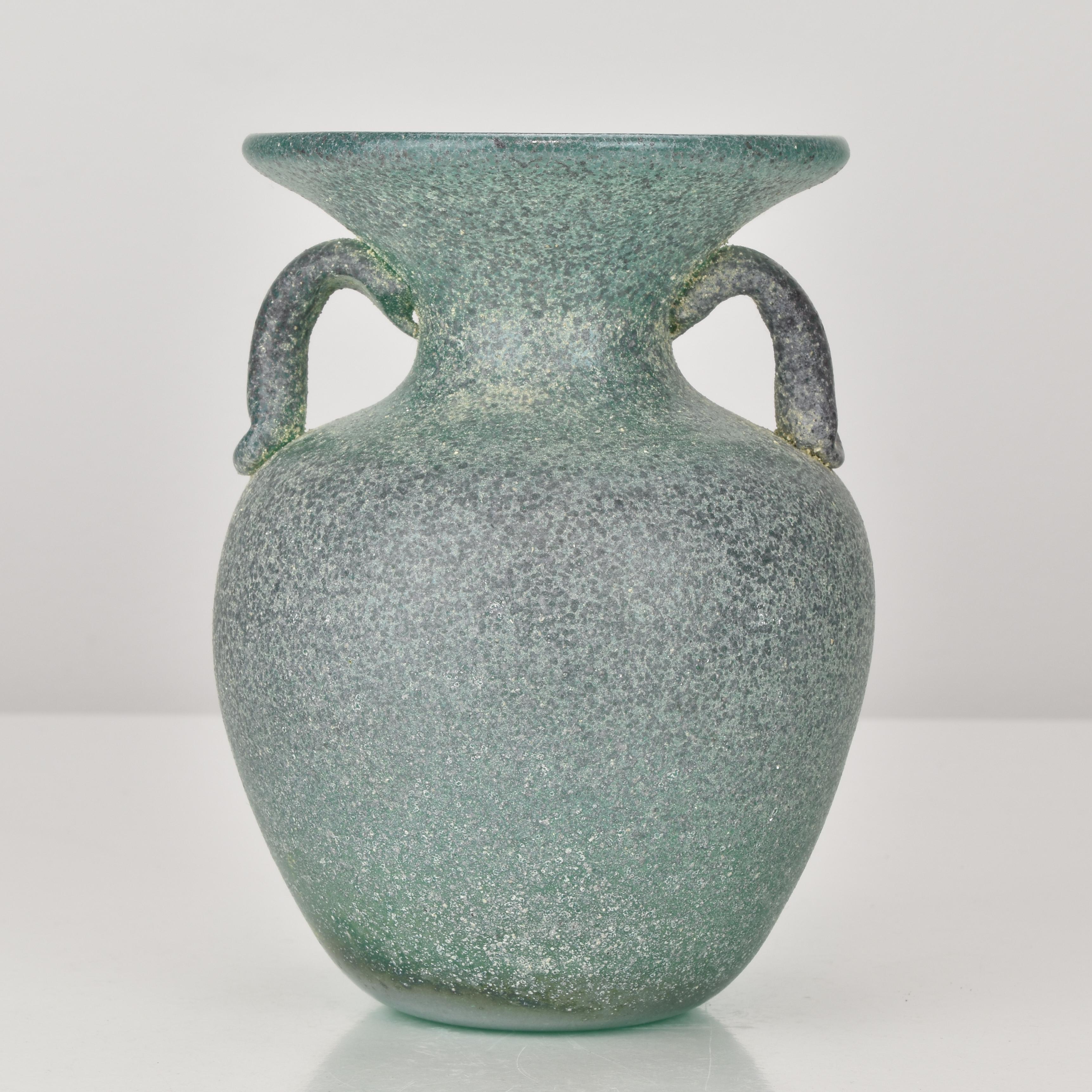 This striking Murano Scavo vase, attributed to Seguso and dating to the 1960s, showcases the refined artistry of mid-century Italian glassmaking. Designed in an elegant amphora form with two applied handles, the piece features a beautifully textured