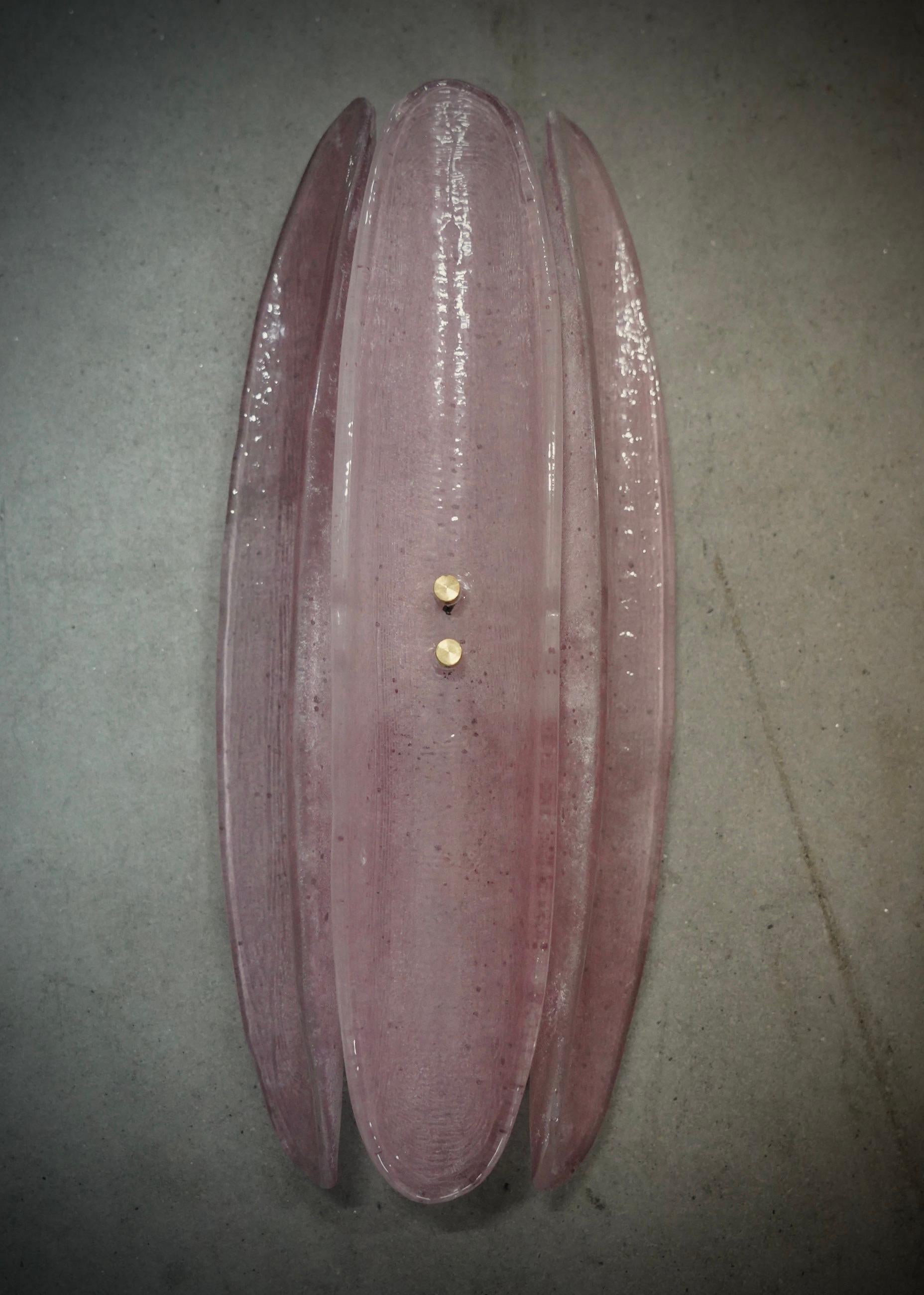 Lampada da parete in vetro di Murano molto originale, con un design molto allungato della mezza conchiglia in vetro e un colore rosa unico.

L'applicazione è costituita da una struttura in metallo color oro a cui sono state attaccate tre