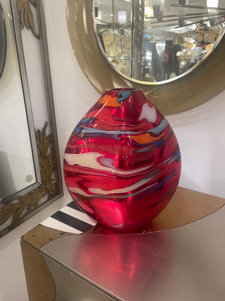 Cet étonnant vase en verre de Murano de forme ovoïde présente une décoration ingénieuse obtenue avec une élégante finition métallique miroitée de couleur rouge.
Cette œuvre d'art, en excellent état, est signée par Davide Conda.