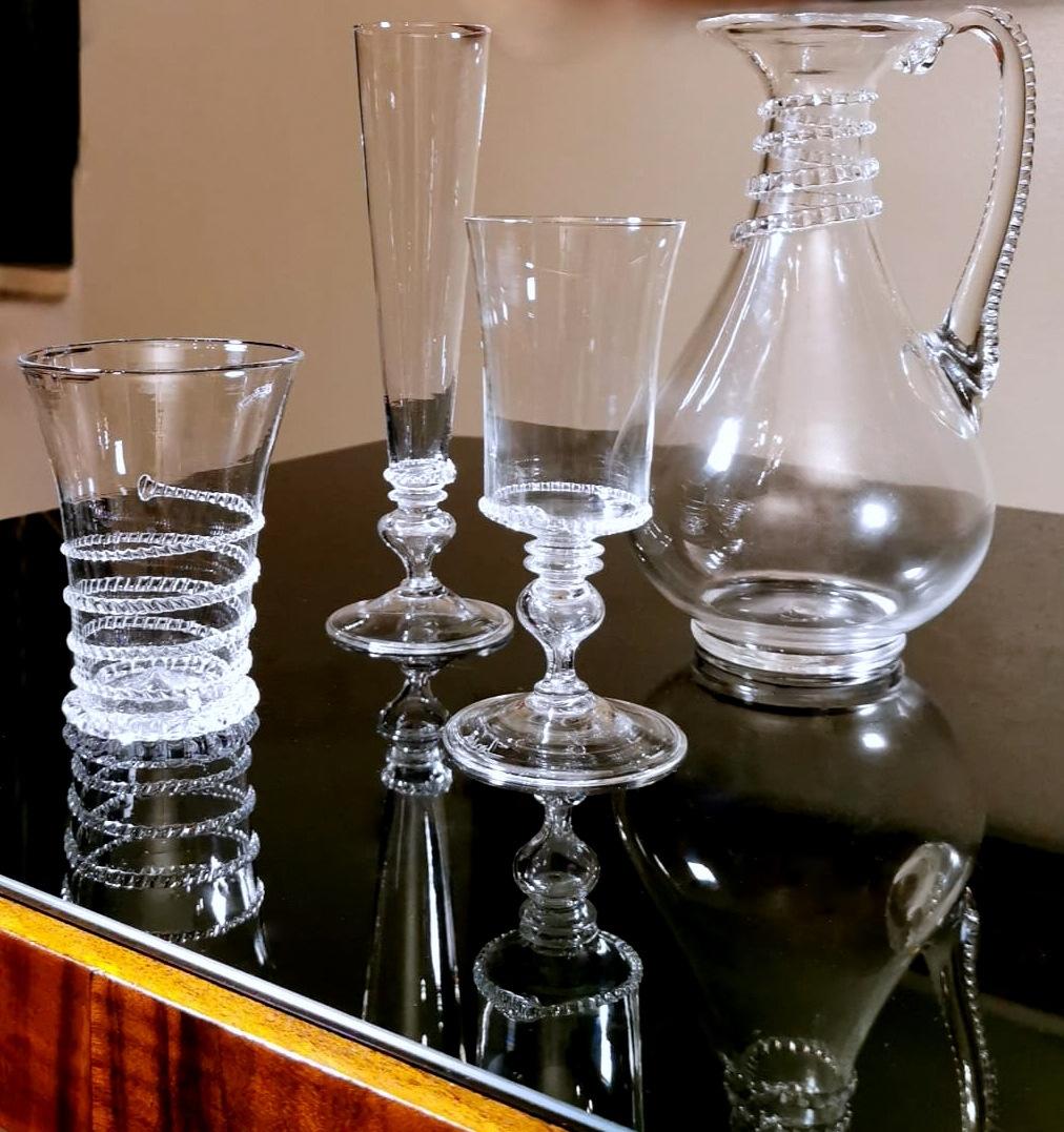 Service précieux et particulier en verre soufflé de Murano ; il est composé de 12 verres à eau, 12 gobelets à vin, 12 gobelets à flûte et d'une cruche avec anse ; le service a été réalisé par un maître verrier de Murano entre 1951 et 1953 qui s'est