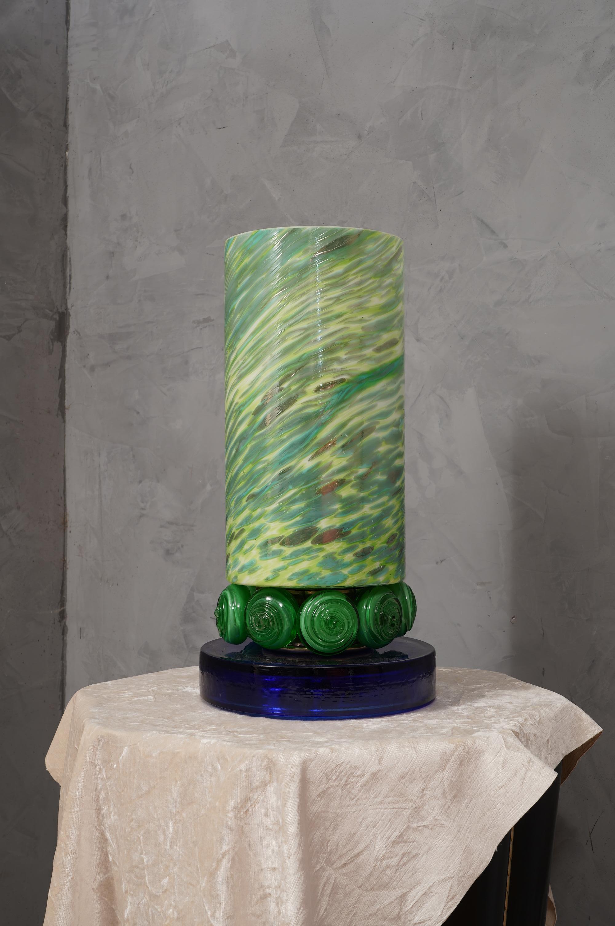 Precious and unique hand-blown Murano white glass, classic but original design with a strong contrast between the large green vase and the blu glass base.

The lamp is characterized by a large green vase with a cylindrical shape, with workings on