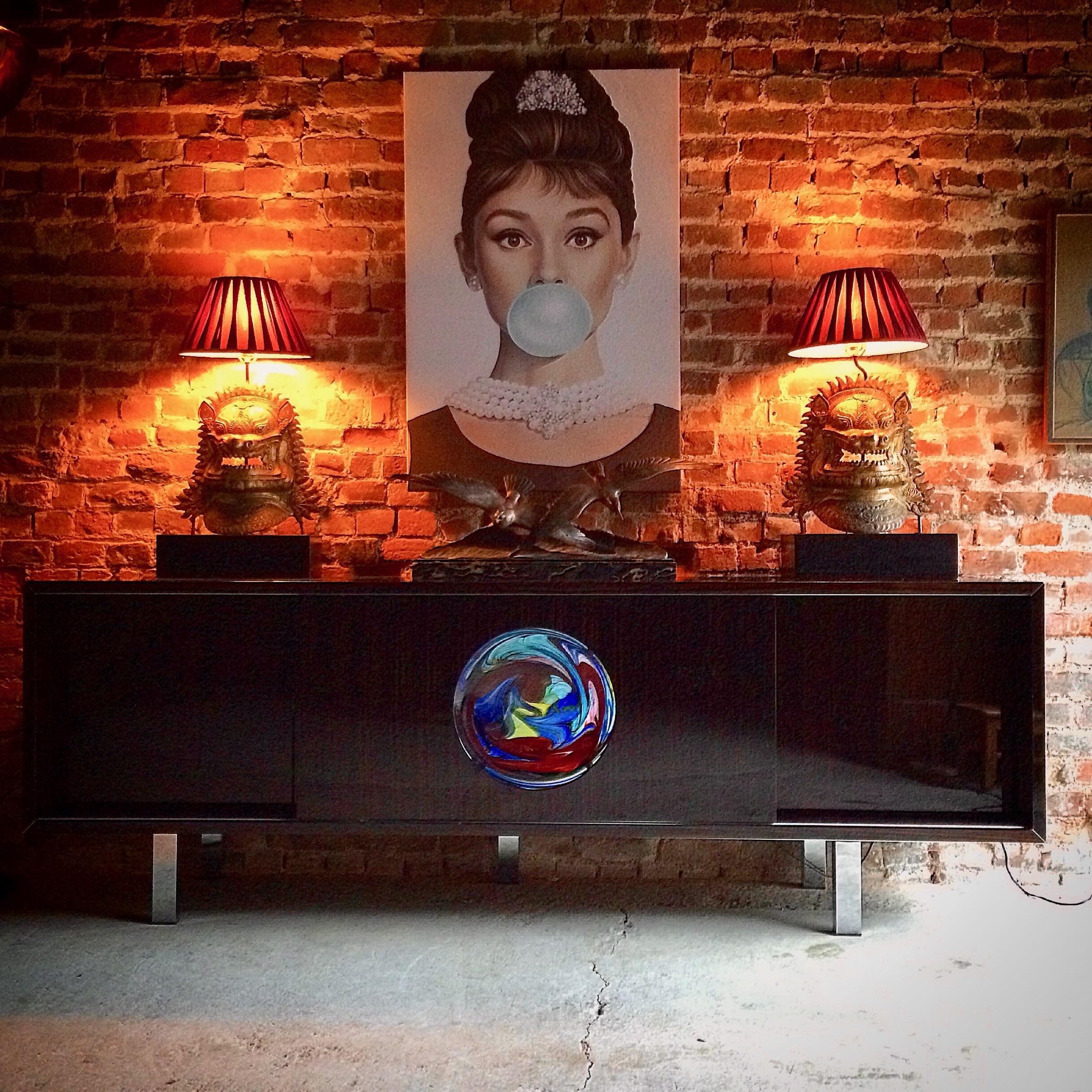 A contemporary Murano sideboard, manufactured by Reflex Angelo, Italy, from the glamour range, with central sliding door, having large roundel of thick colored Murano glass, the glass bearing Vetri Artistico label, with illuminated cupboard behind,