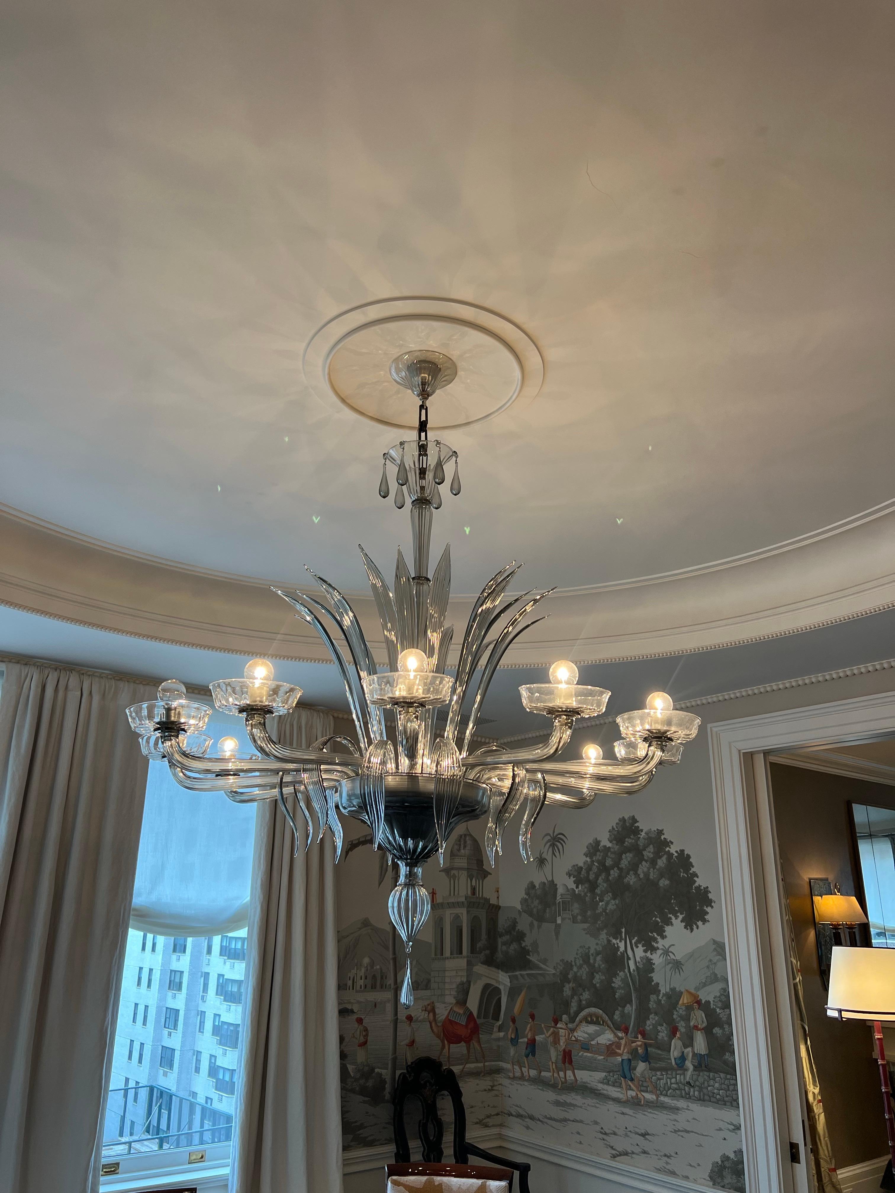 Lampadario in vetro colorato di Murano a dodici luci, C.C. 1980.
Foglie alte e soffiate adornano lo stelo centrale verso l'alto. Dodici bracci si estendono con foglie curve e dinamiche che puntano verso il basso in un design elegante e raffinato.
