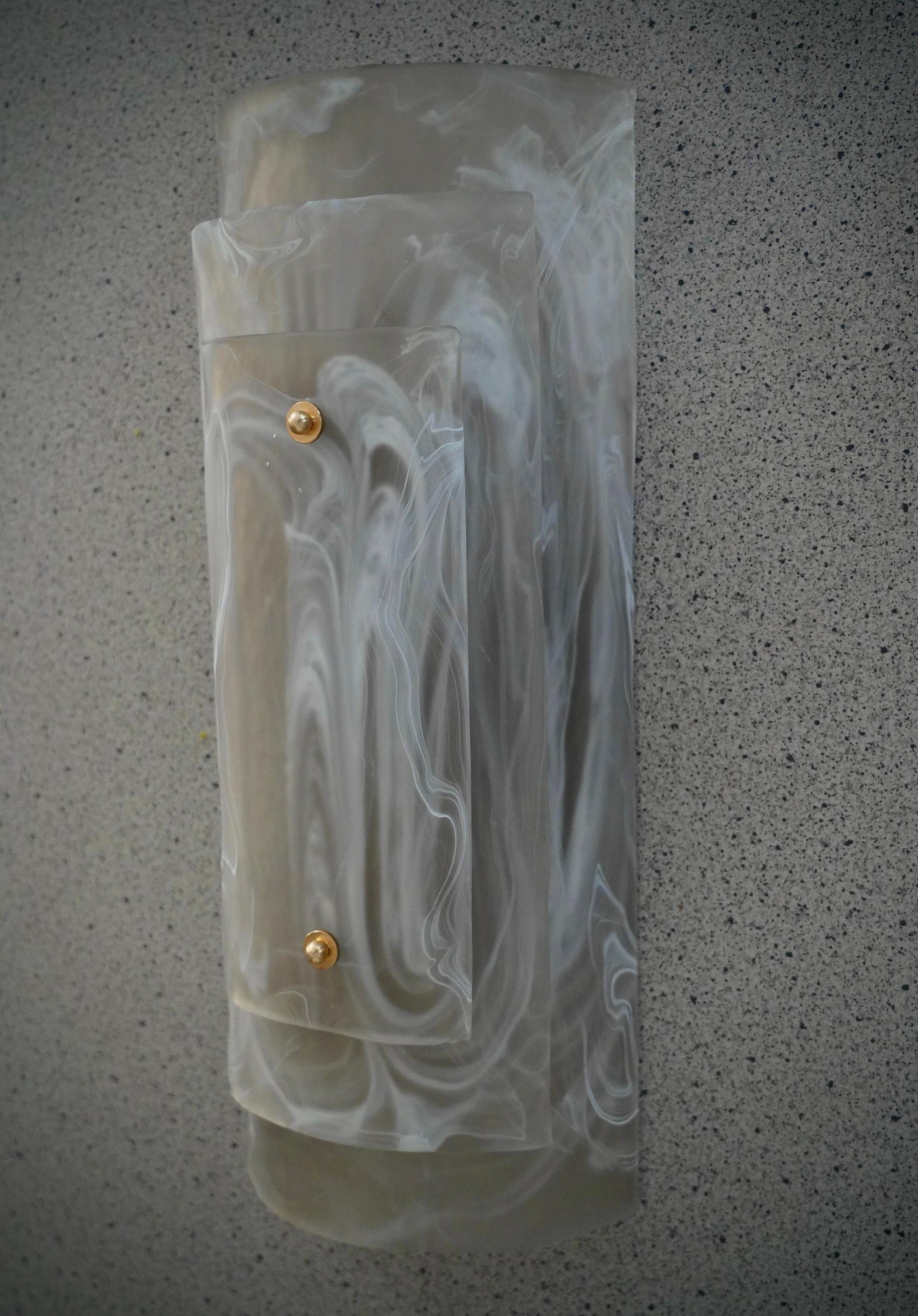 Este aplique de cristal de Murano presenta un bello montaje. Un cristal muy singular y raro, con un efecto ahumado con vetas blancas; estilo clásico de Murano.

El aplique está fabricado con un hermoso cristal ahumado liso, curvado para formar un