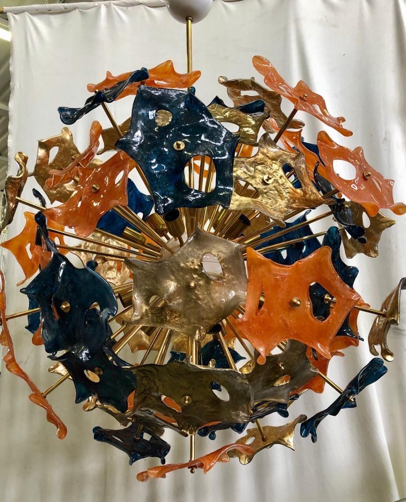 Large and particular glass handkerchiefs, as if they were butterflies, make up this beautiful Murano chandelier, plus with three bright and original colors orange gold and blue.

Made of a large central sphere in which brass rods are screwed, glass