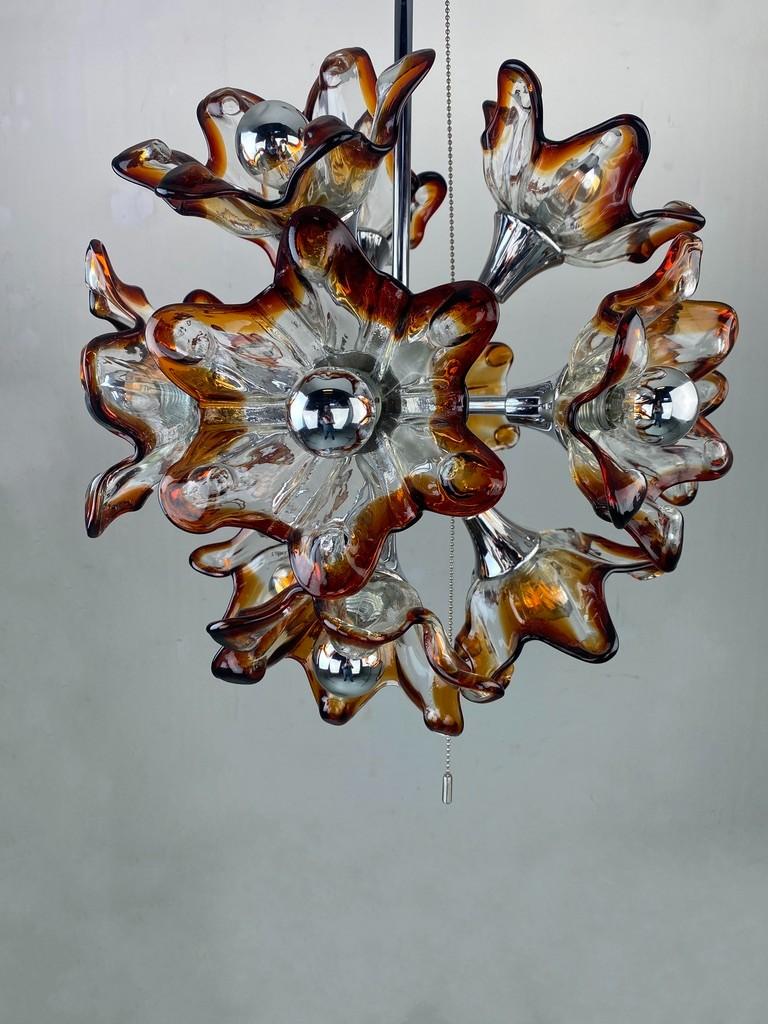 Breathtaking flower sputnik chandelier in the style of Mazzega. Sumptuous and chic. In a very good and working condition. The calyces are made of mouth-blown Murano glass. The edges of the chalices have a light and dark amber colour like Mazzega.