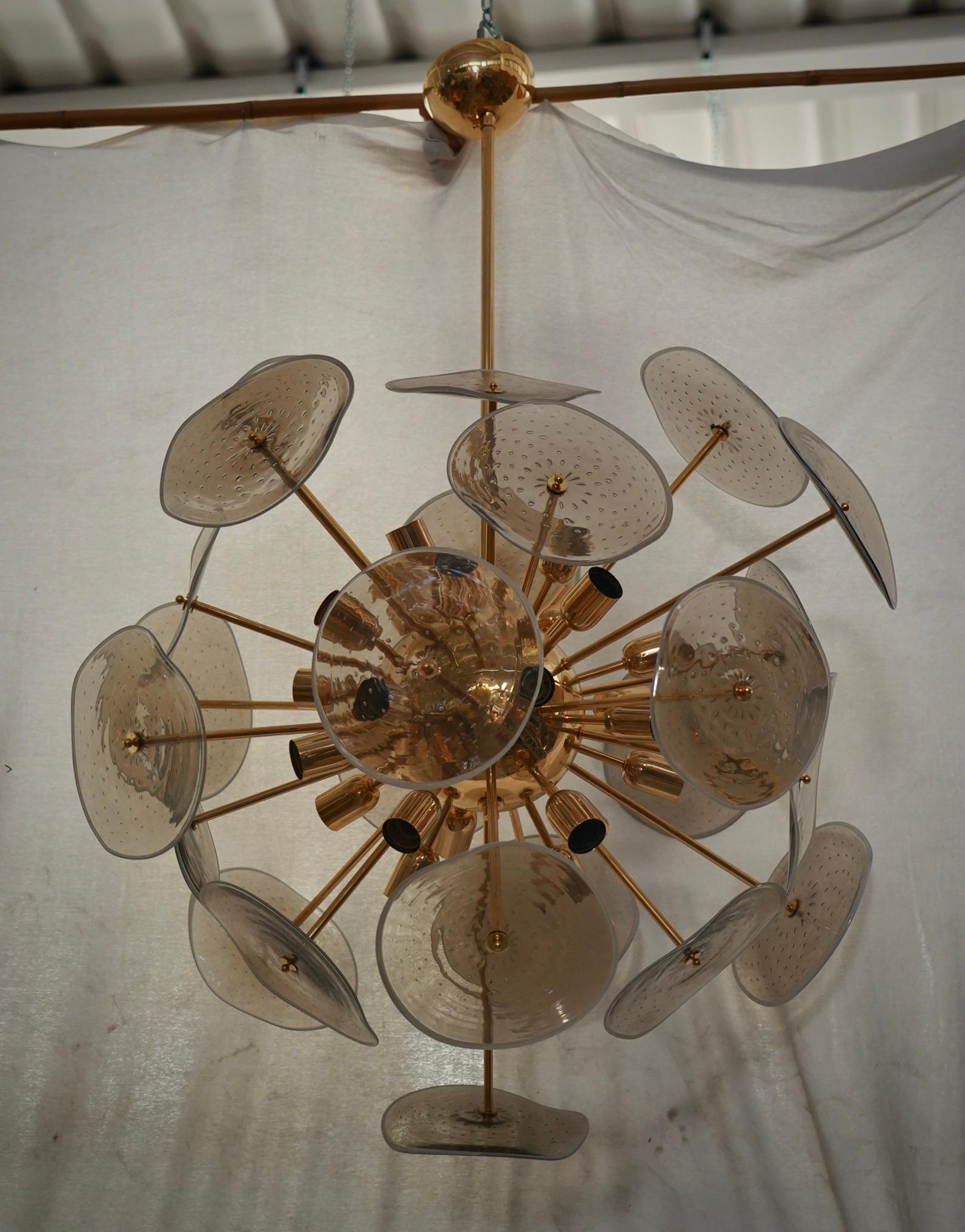 De grandes plaques de verre fumé, transparent et cerclé, composent cet étonnant lustre de Murano. Un Sputnik classique du milieu du siècle.

Elle présente une grande sphère centrale dans laquelle sont vissées des tiges de laiton, au-dessus