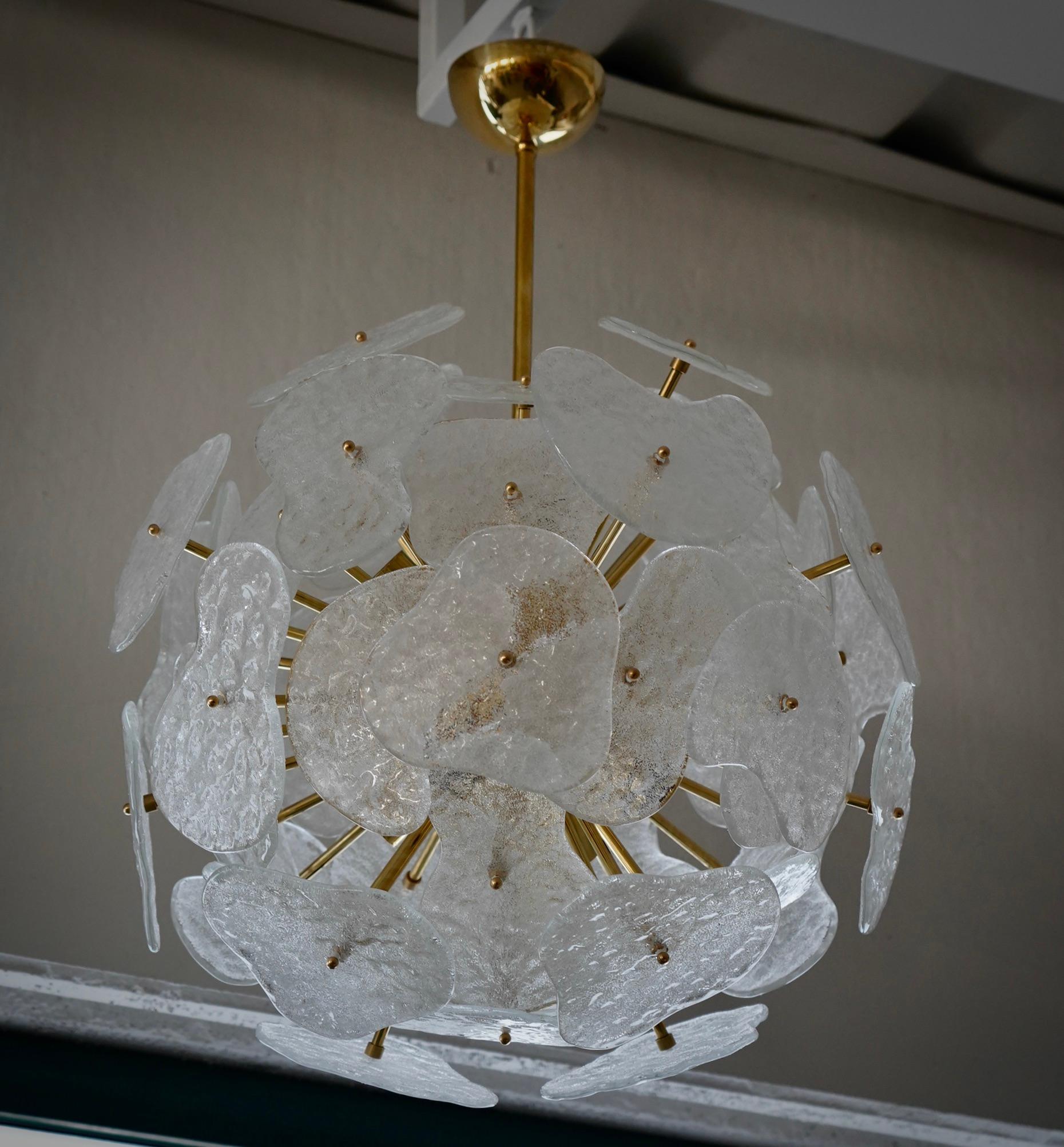 Grandes flores de cristal transparente componen esta impresionante lámpara de Murano. Un Sputnik clásico de mediados de siglo.

Presenta una gran esfera central con varillas de latón atornilladas, rematada con hojas de cristal. Tiene ocho puntos de