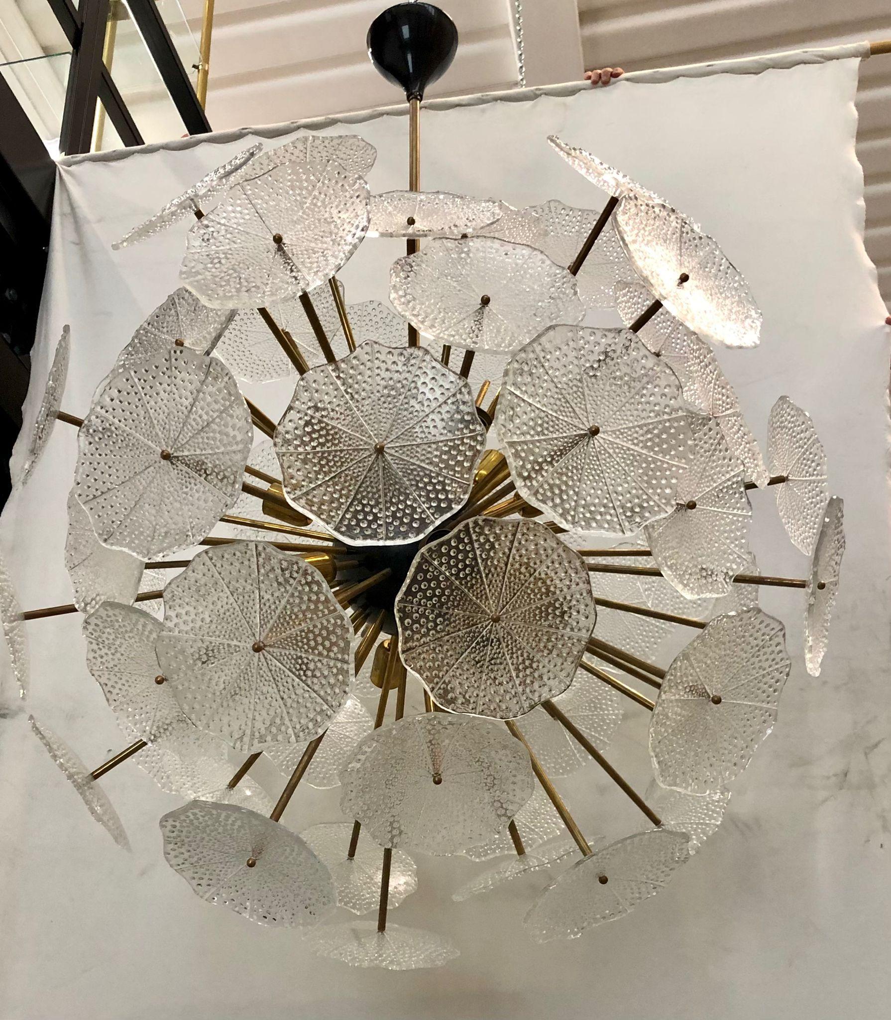 The large glass flowers make up this Murano chandelier from the 1980. A Classic Sputnik from the middle of the century.

Made of a large central sphere in which brass rods are screwed, glass leaves are placed above the brass rods. It has 18-light